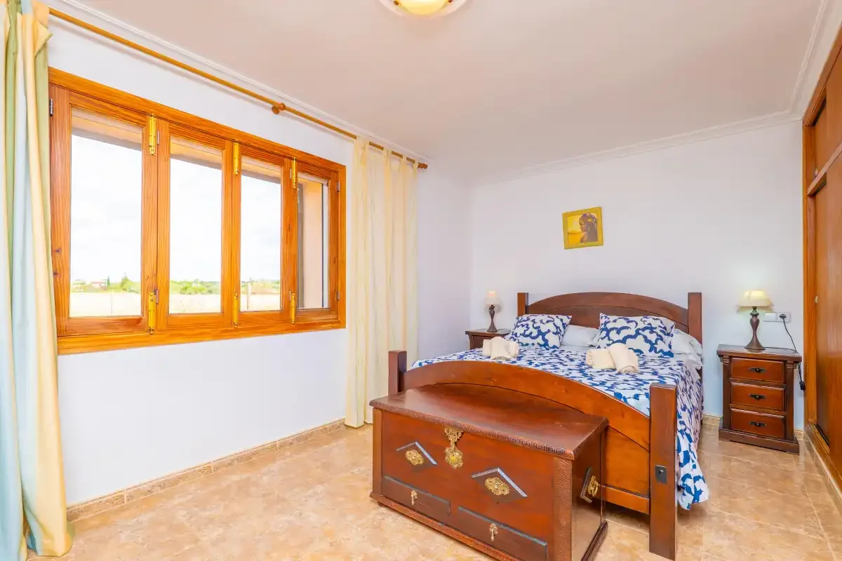 A bedroom with a wooden bed and a large window.