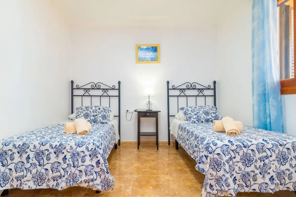 A bedroom with two single beds dressed in blue-and-white patterned bedding.