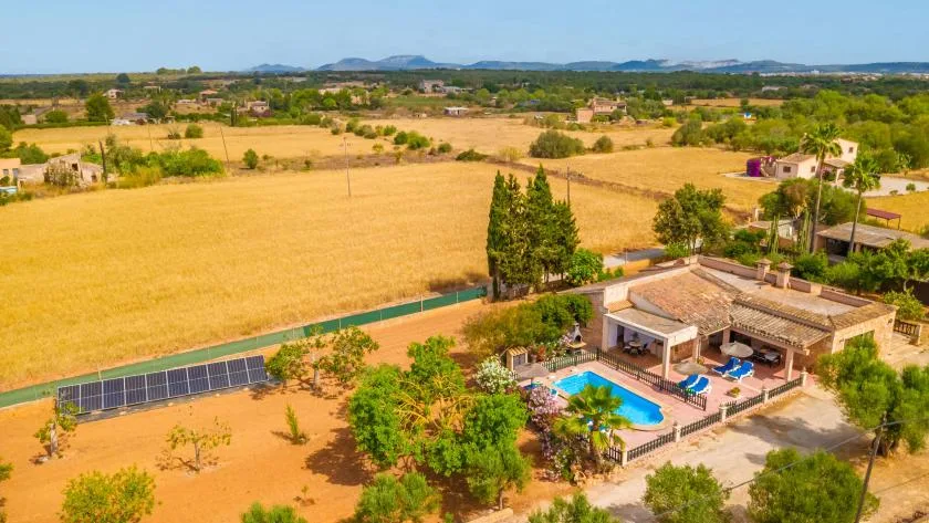 A countryside property with a swimming pool beside open fields.