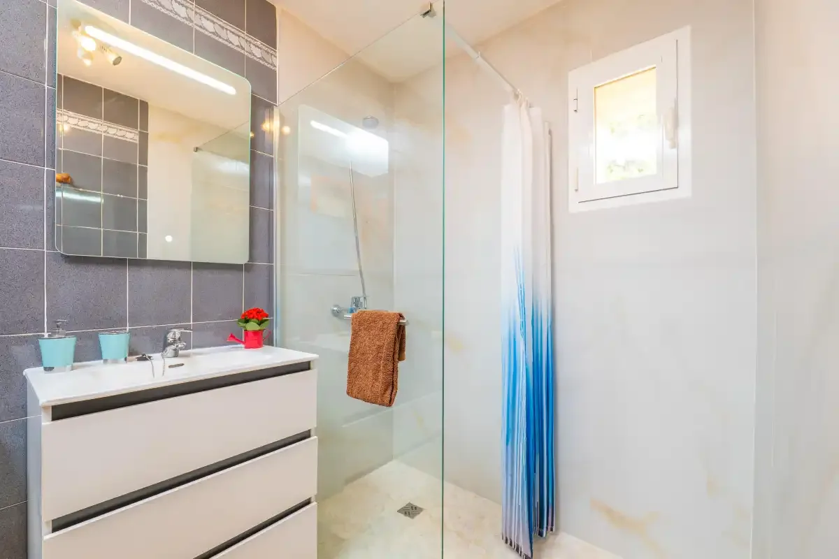A bright bathroom with a sink vanity and glass shower.