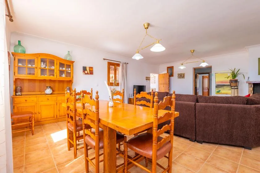 A dining and living area with a wooden table and seating beside a brown sofa.