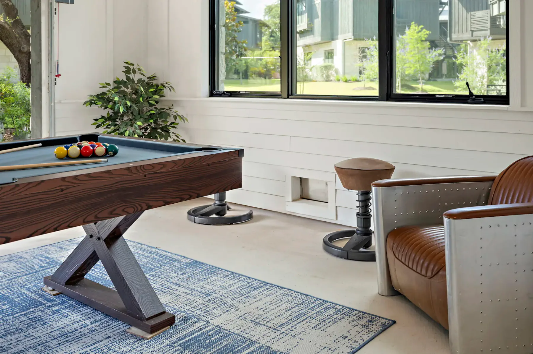 A game room with a pool table, seating, and large windows.