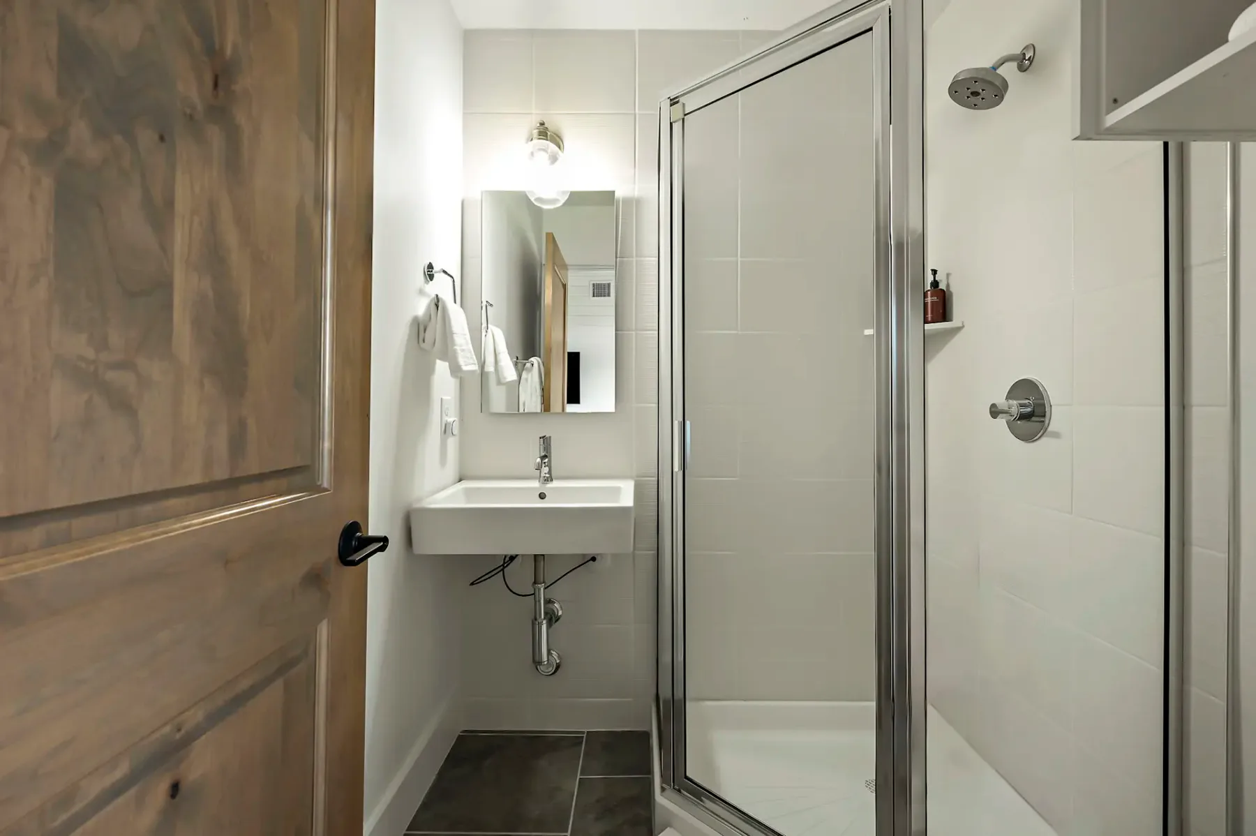 A bathroom with a sink and mirror beside a glass shower.