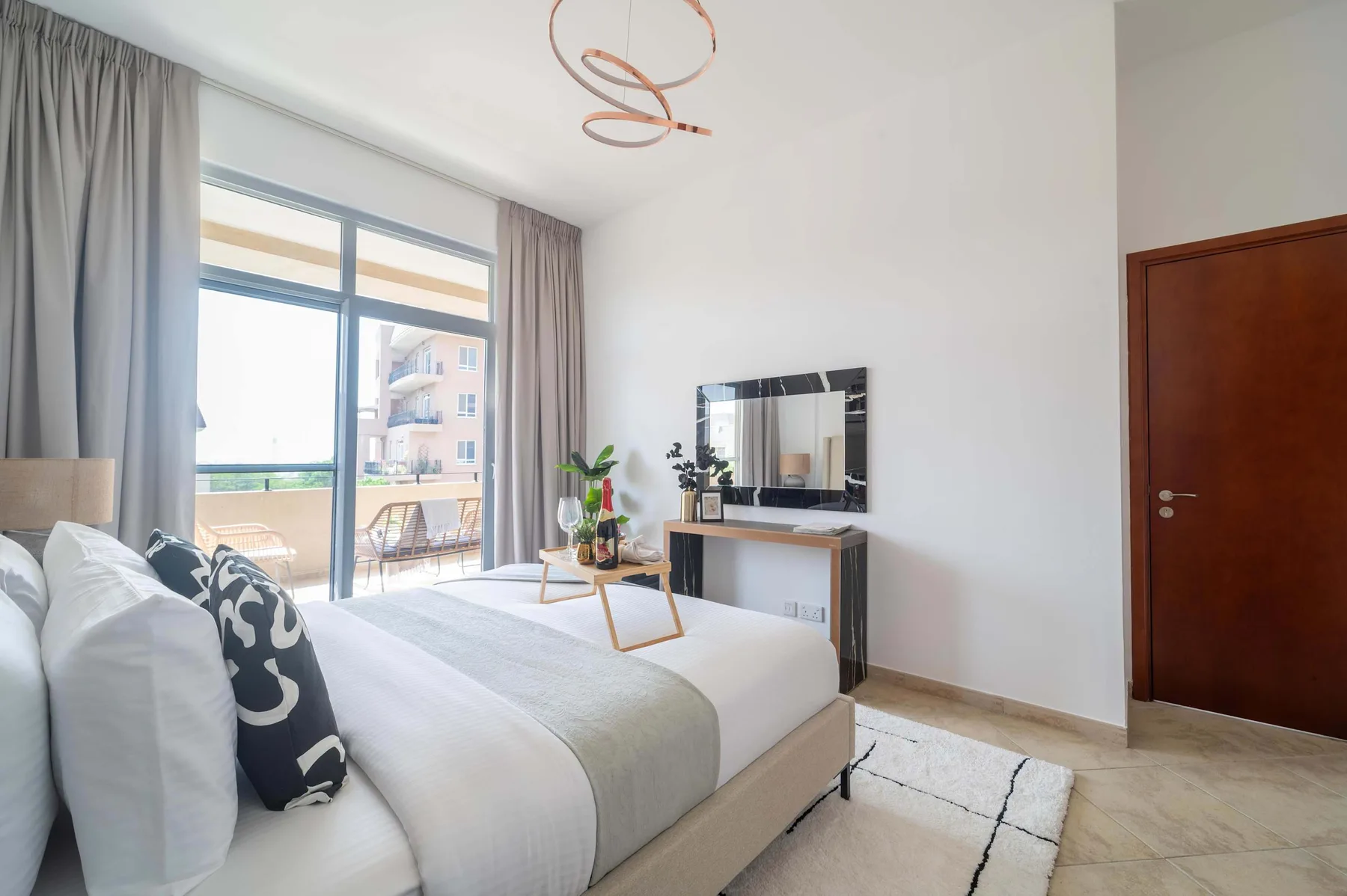 Un dormitorio luminoso con una cama junto a una gran puerta de vidrio que da a un balcón.