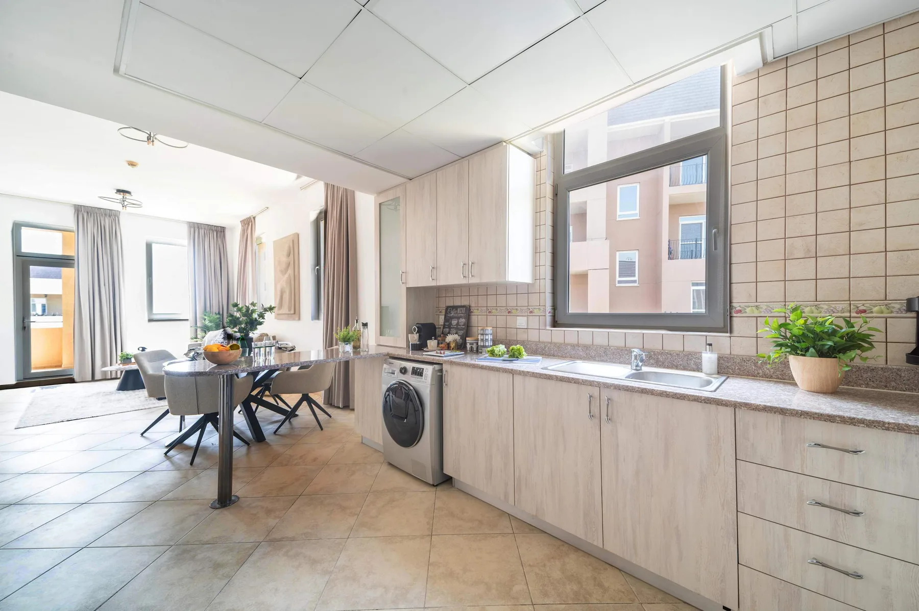 Una luminosa cocina y zona de comedor con una encimera larga y una mesa.