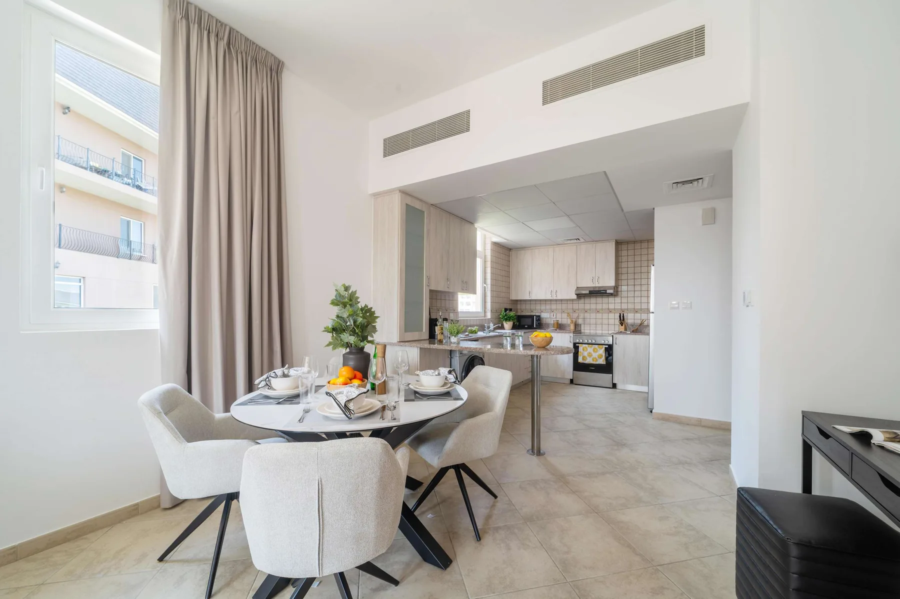 Un comedor se abre a la cocina, con una mesa redonda junto a la ventana.