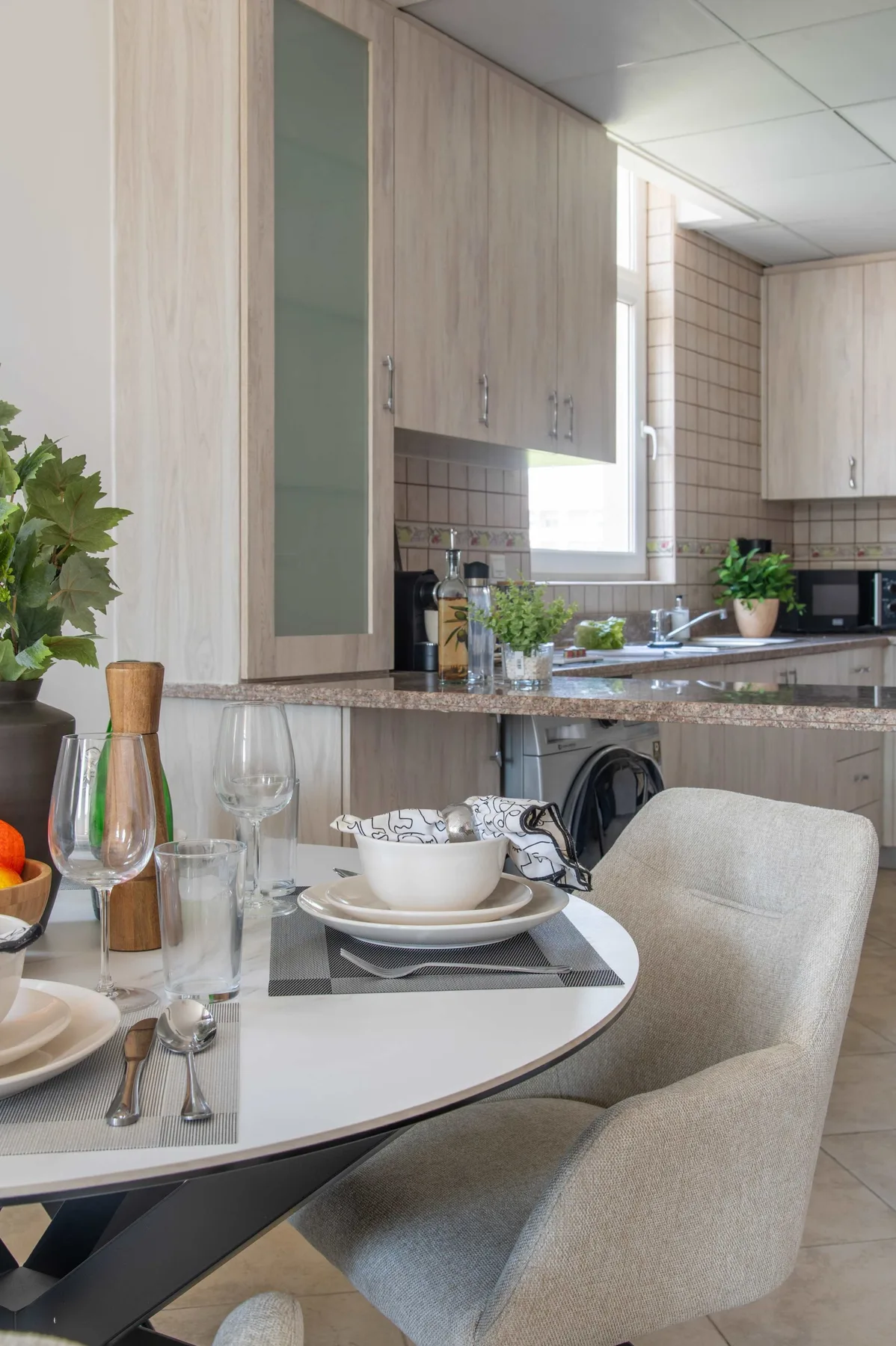 Comedor con la mesa puesta junto a una encimera y armarios de cocina.