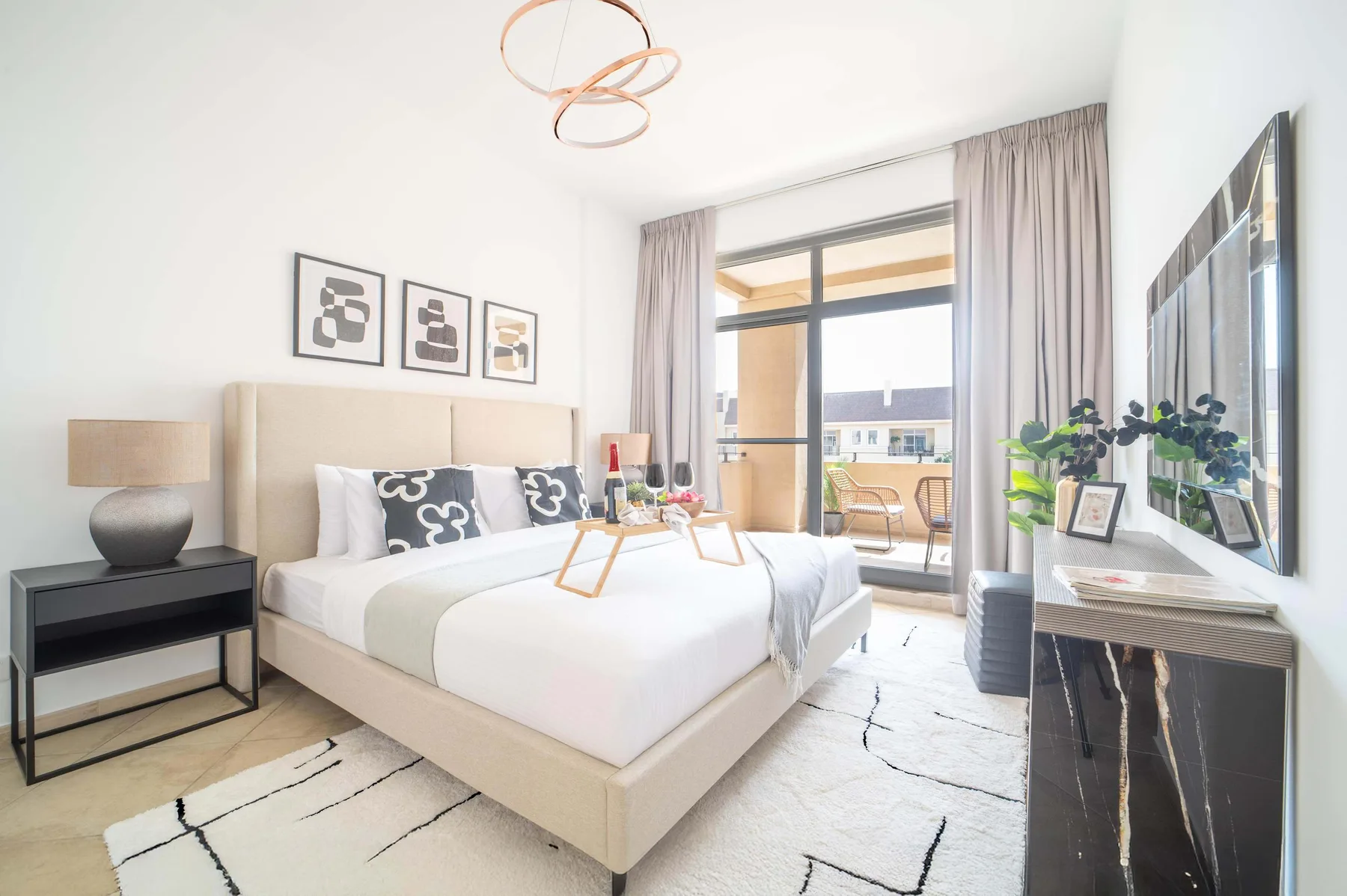 Un dormitorio luminoso con una cama tendida y grandes ventanas.