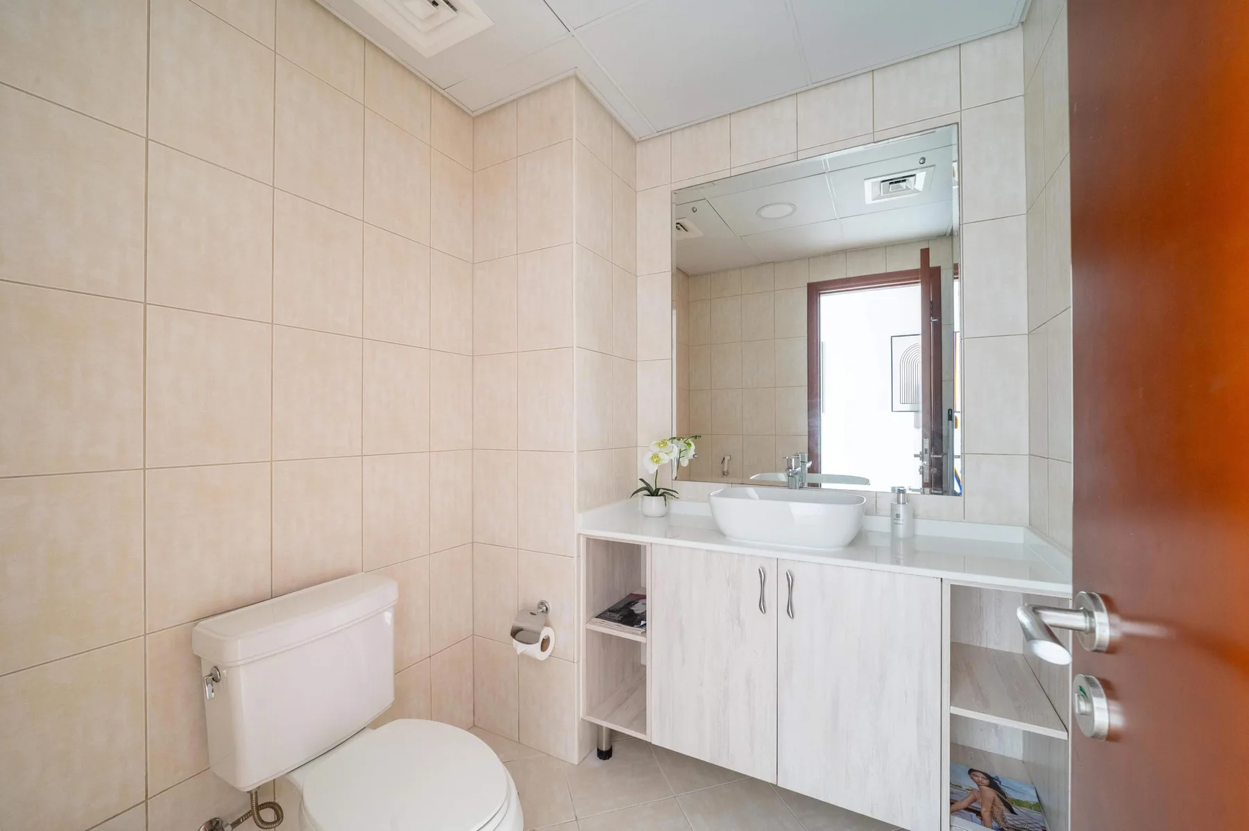 Un baño con azulejos, lavabo, espejo e inodoro.
