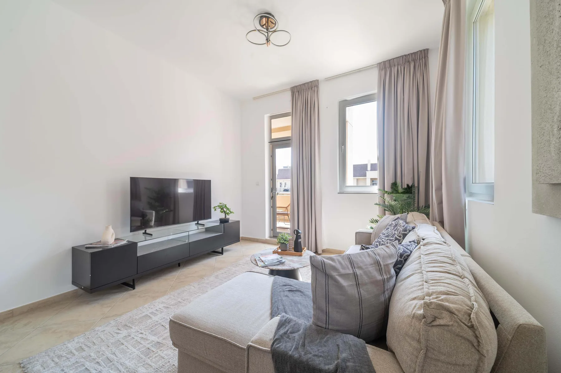 A bright living room with a large sectional sofa and a television.