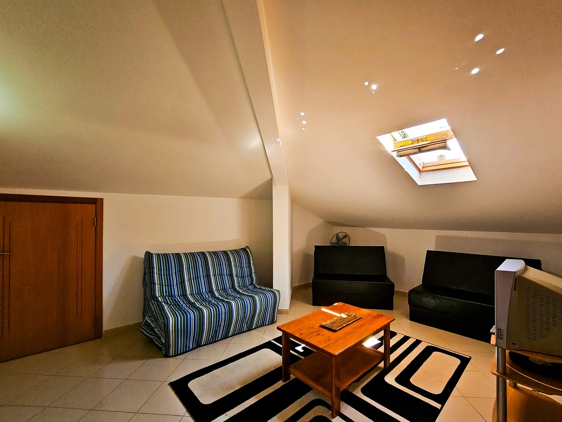 A living room with seating, a coffee table, and a skylight.