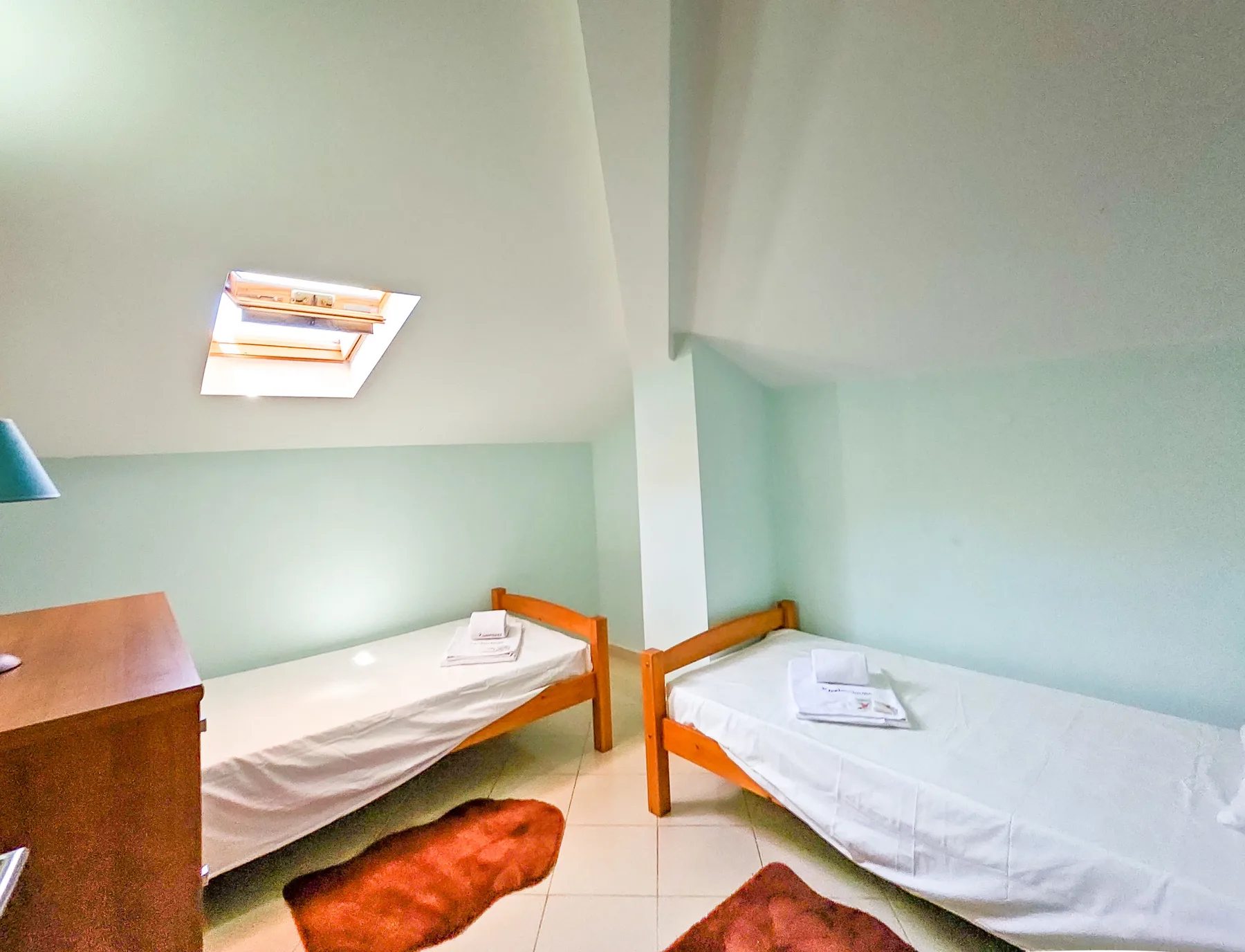 A compact bedroom with two single beds beneath a sloped ceiling.