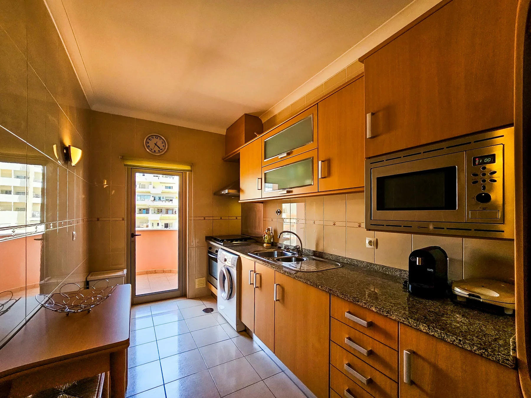 A narrow kitchen with wooden cabinets, a countertop, and built-in appliances.