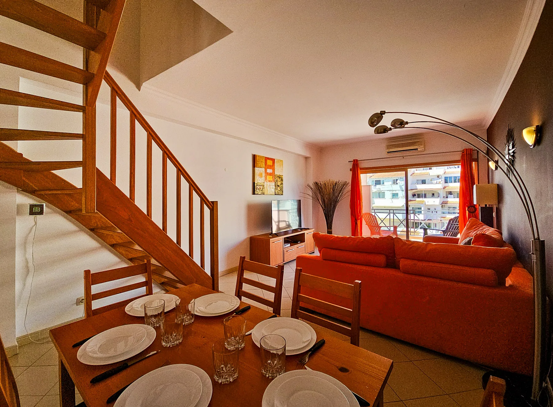 A living and dining area with a table, seating, and a staircase.