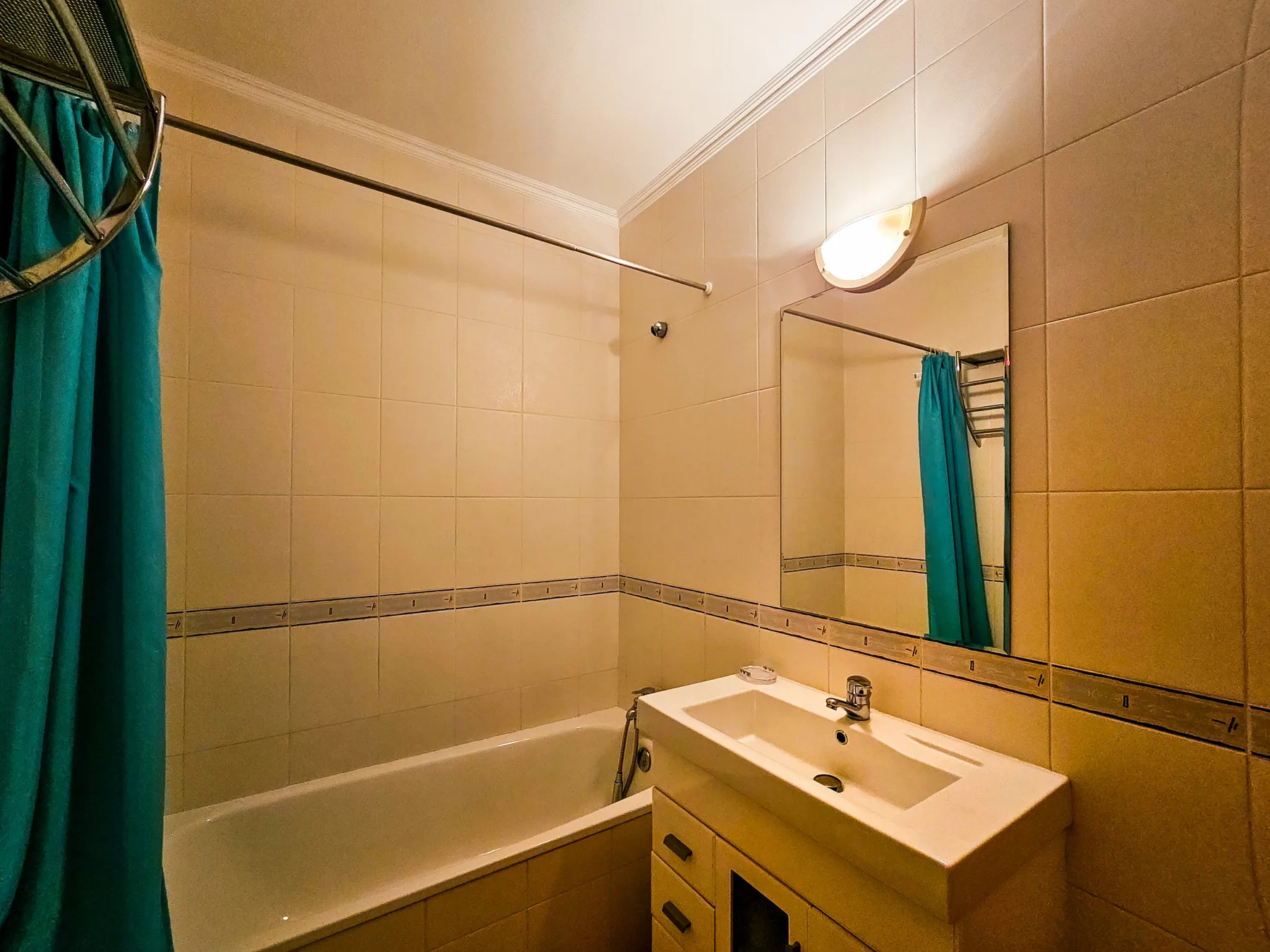 A tiled bathroom with a bathtub, sink, and mirror.