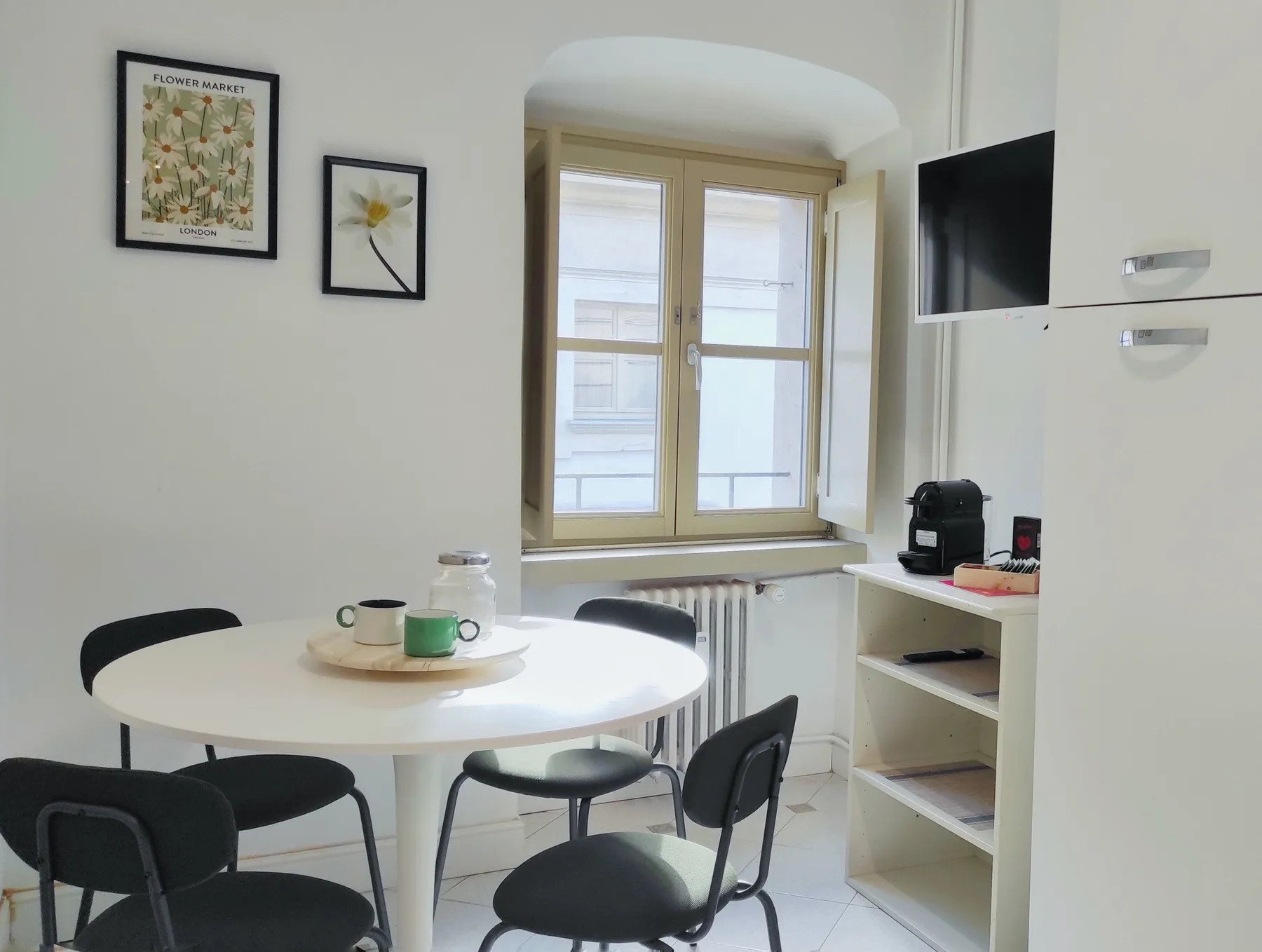 Un comedor luminoso con una mesa redonda junto a una ventana y estantes abiertos.