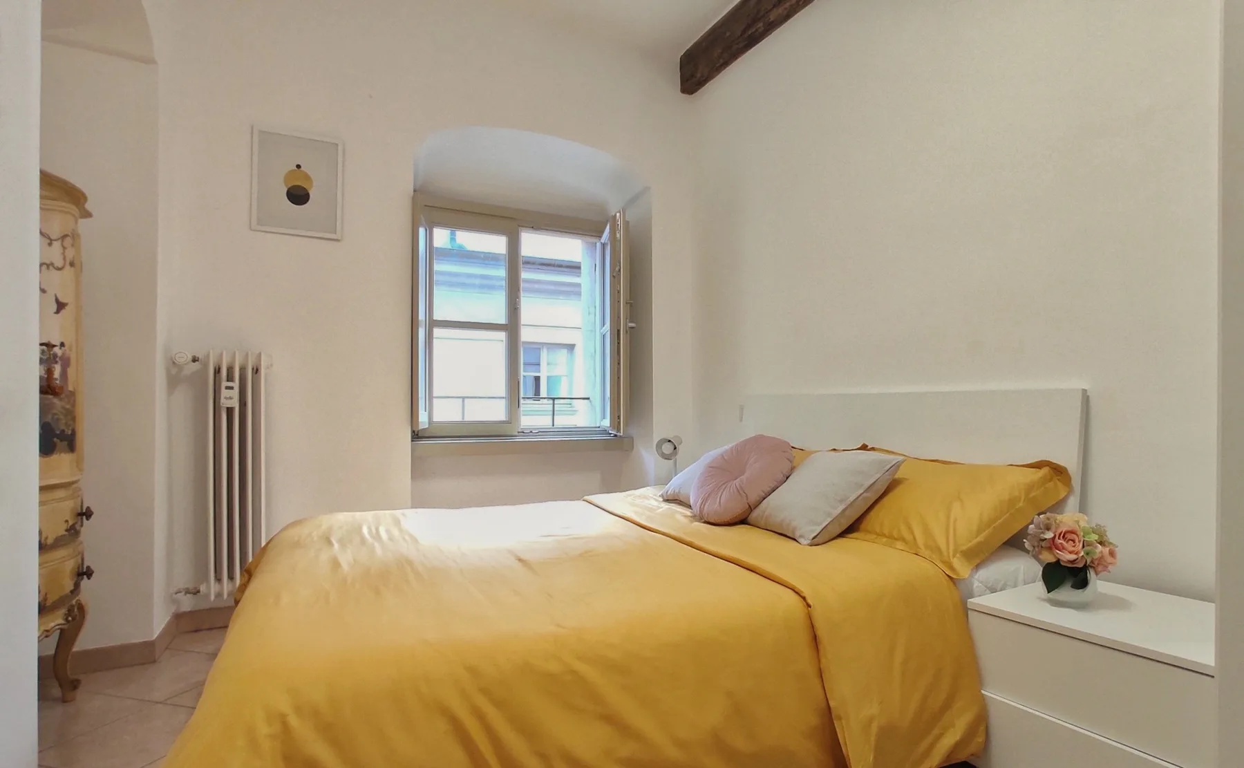 Un dormitorio con una cama vestida de amarillo junto a una ventana.