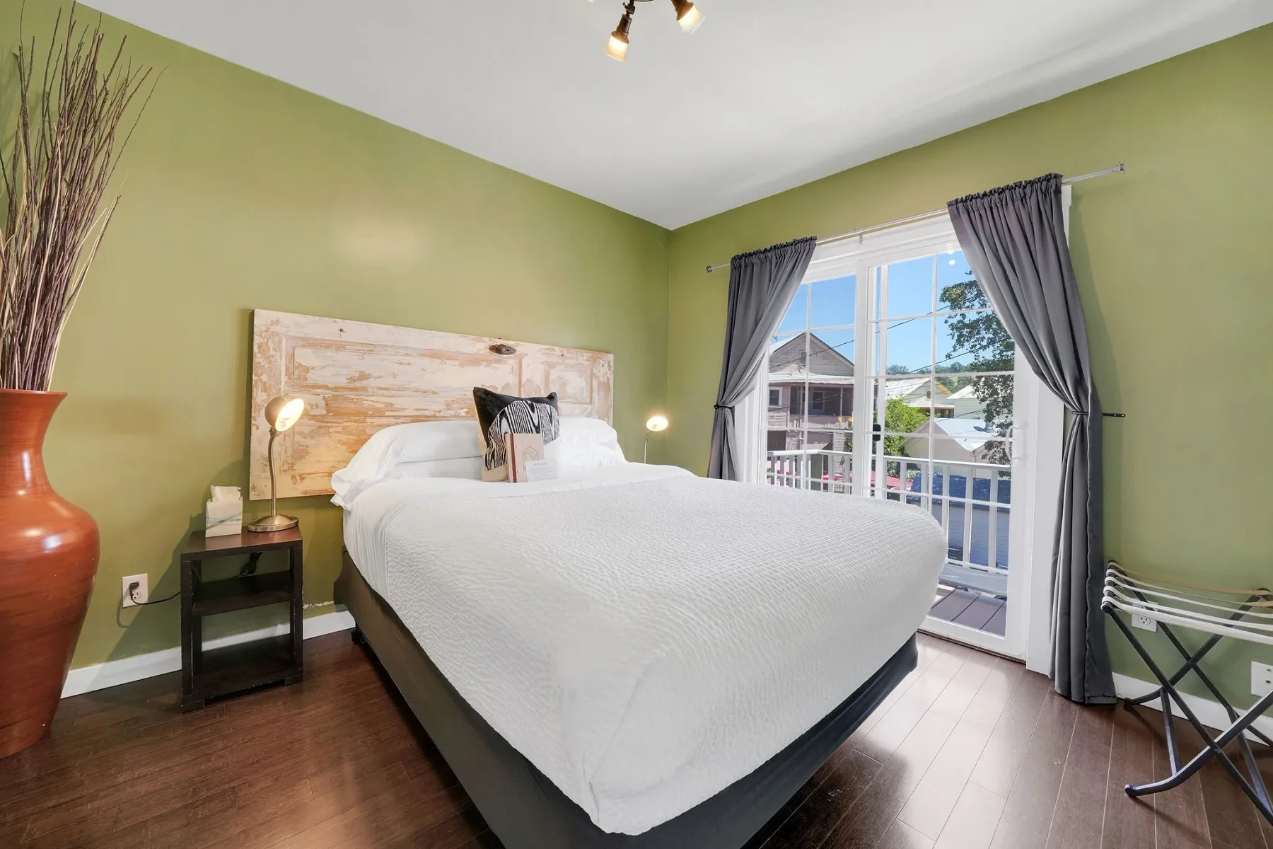 Dormitorio de bungaló con paredes verdes y una puerta corrediza de vidrio.