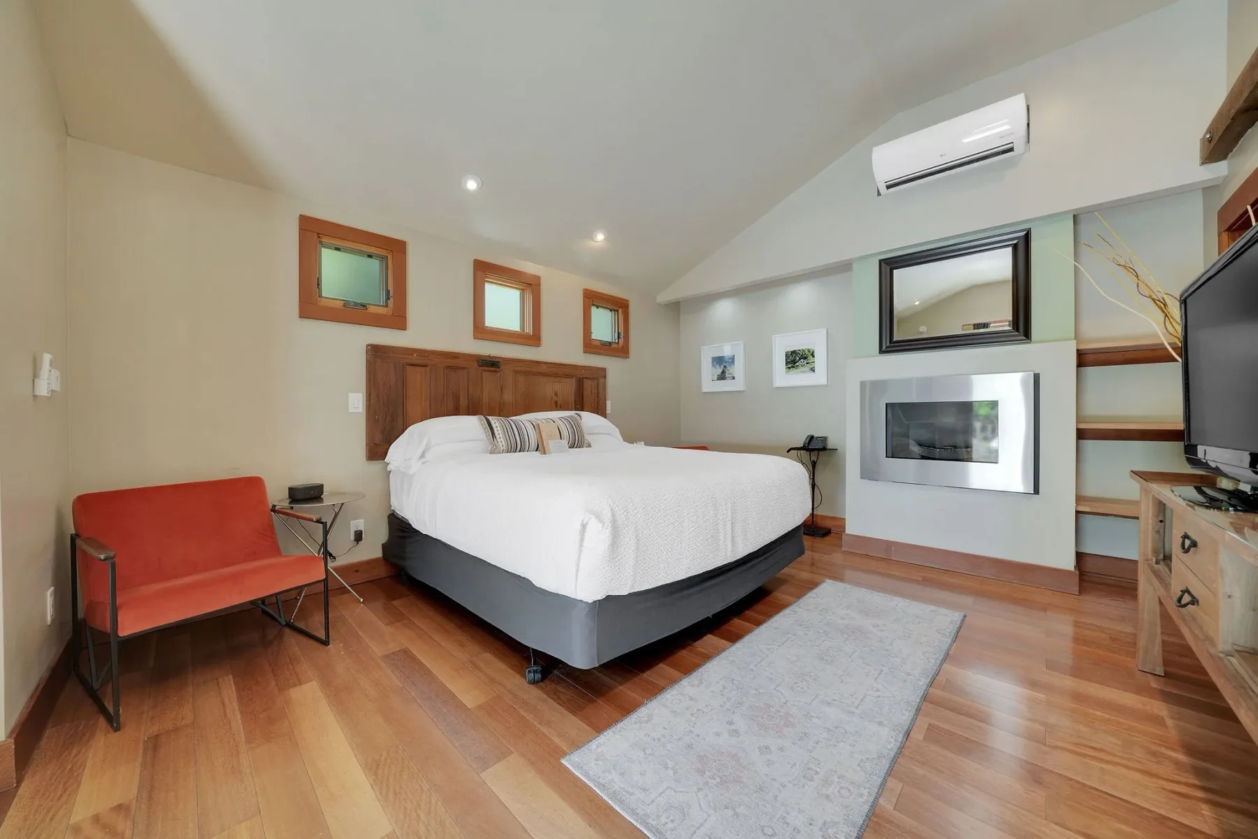 Dormitorio con piso de madera, chimenea y cama.