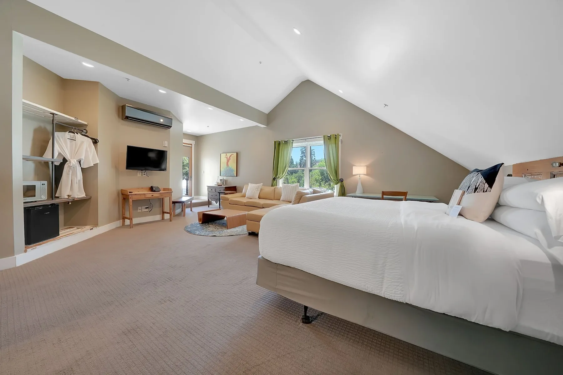 Habitación con una cama, zona de estar y ventanas grandes.