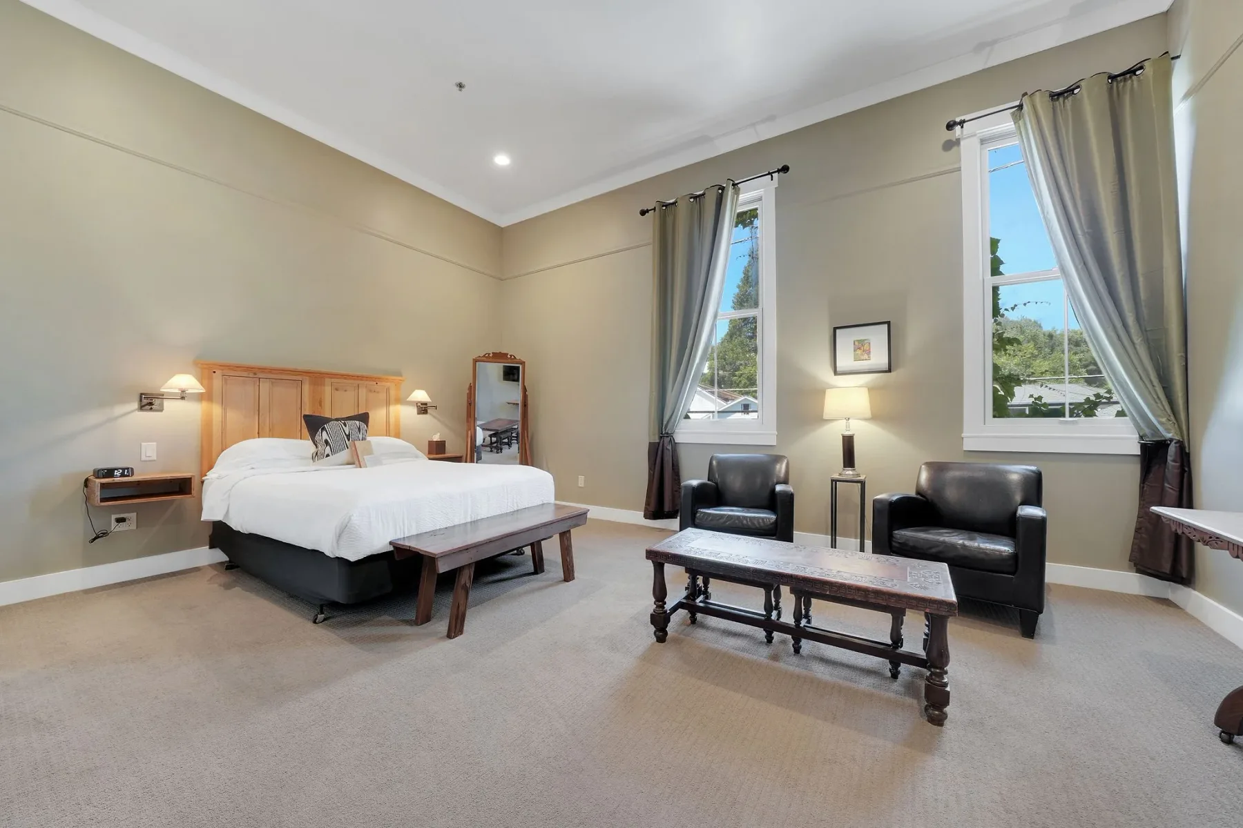 Habitación estándar con una cama grande y dos sillones.