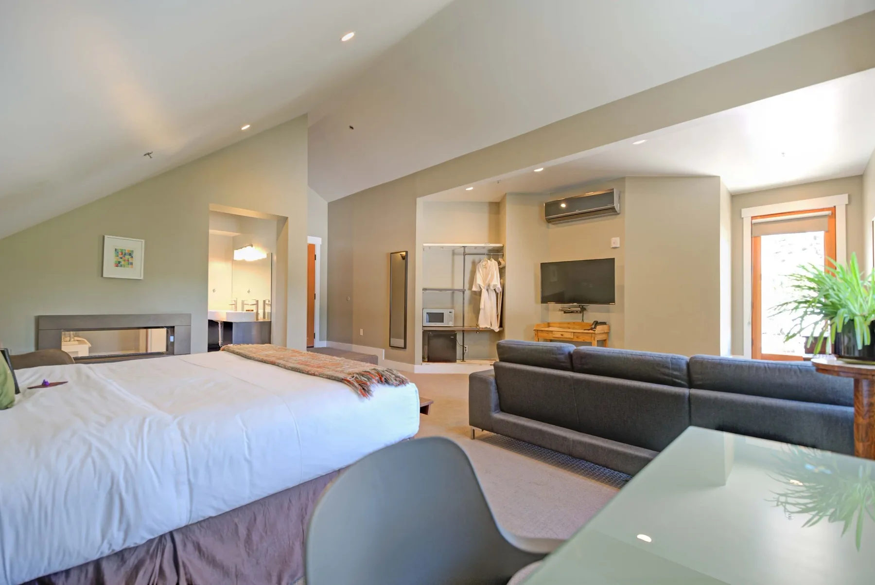 Habitación de hotel con una cama king, zona de estar y zona de cocina pequeña.