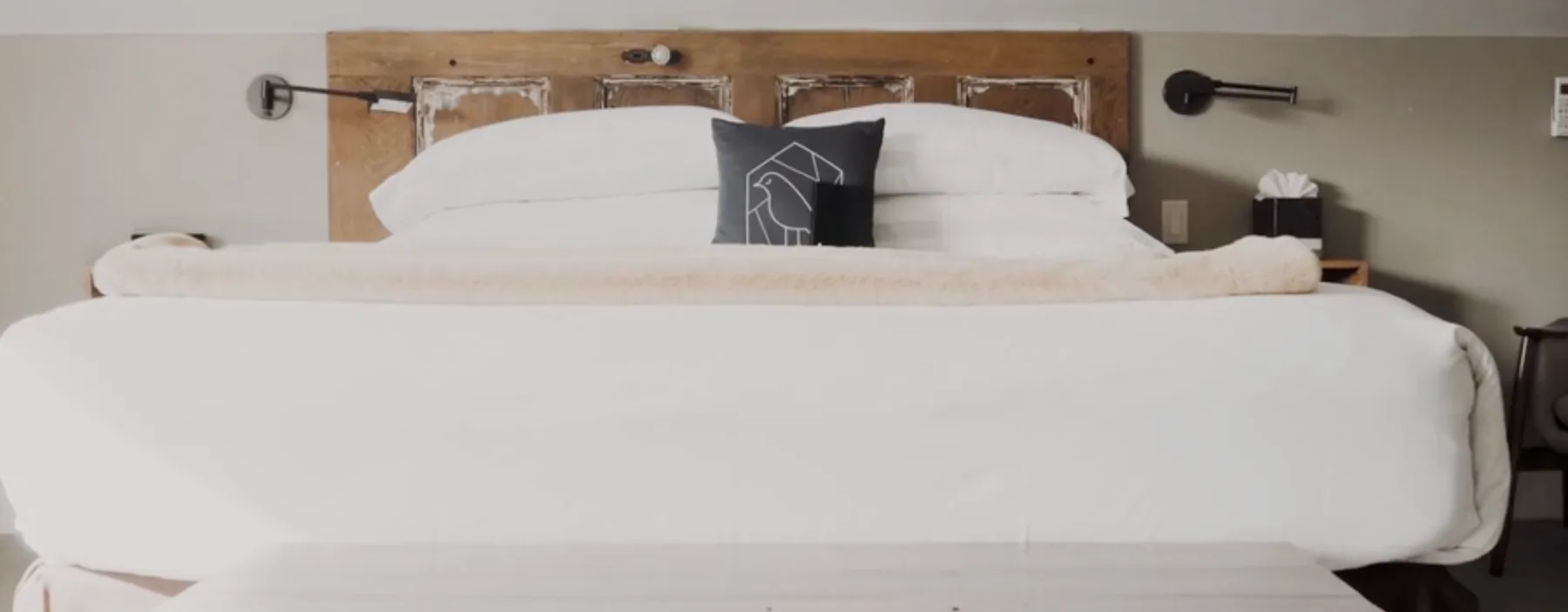Cama de hotel con cabecero rústico de madera.
