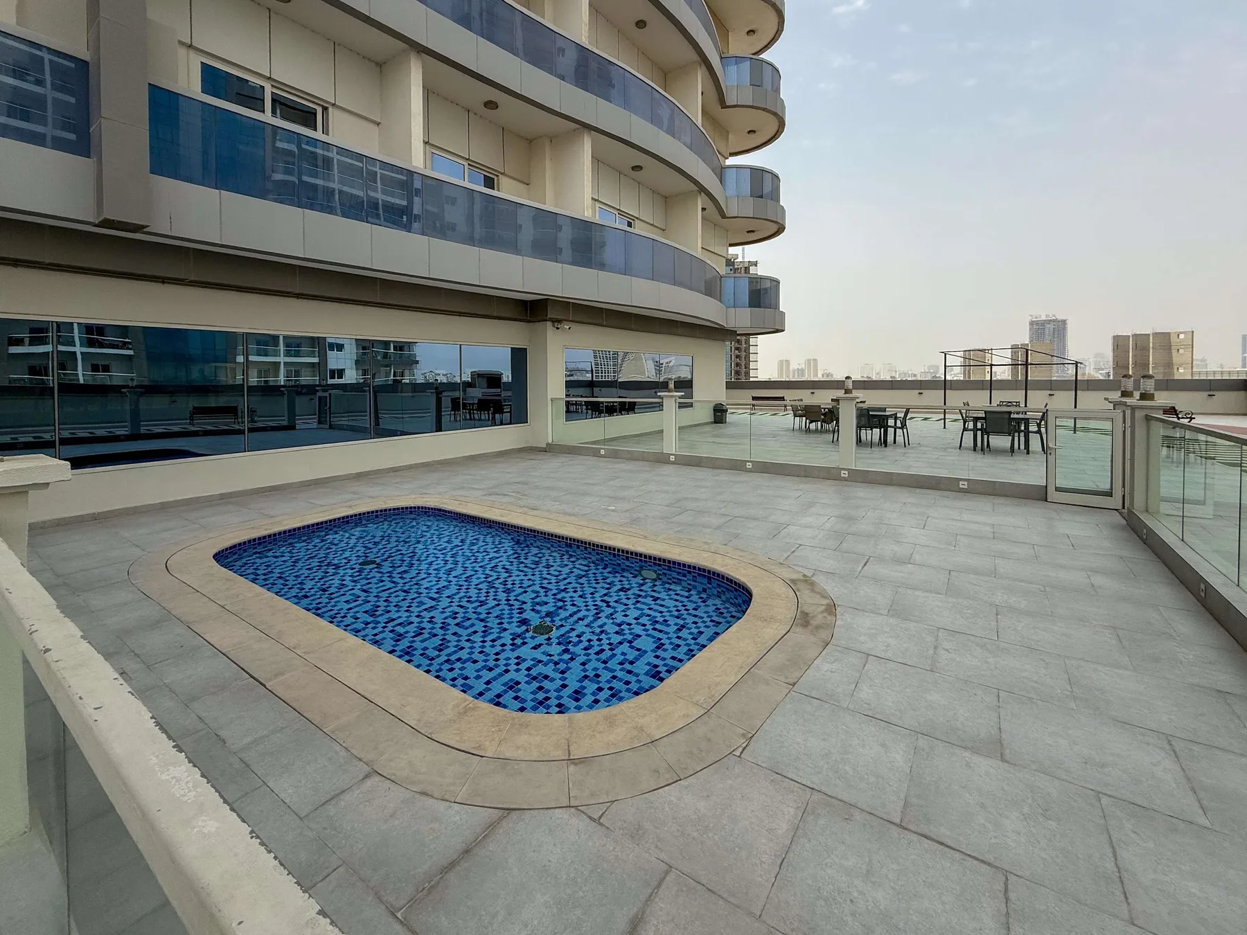 Una terraza en la azotea con una pequeña piscina azul y asientos al aire libre.