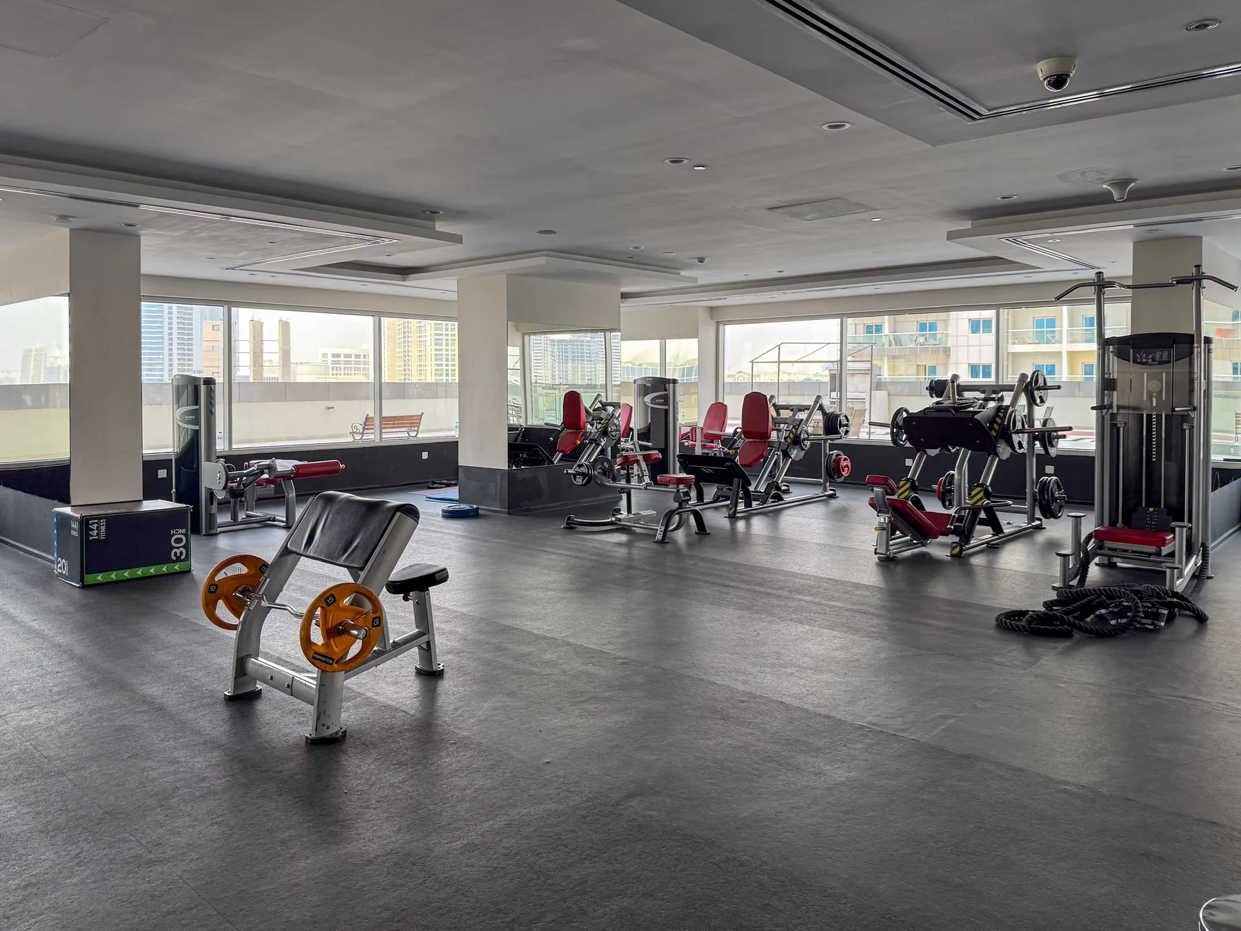 Un gimnasio amplio con máquinas de ejercicio y grandes ventanas.