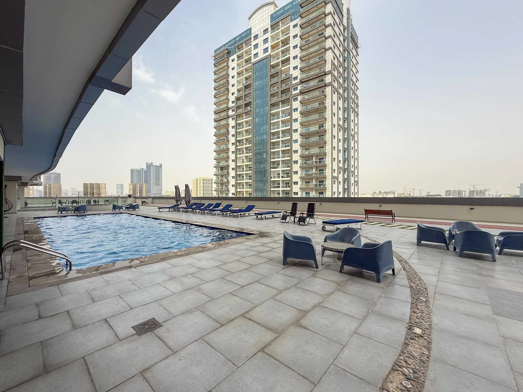 Una piscina en la azotea está rodeada de una terraza embaldosada y asientos.