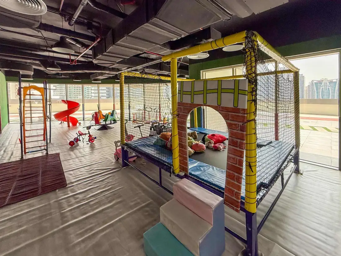 Un área de juegos infantil interior tiene estructuras acolchadas y juguetes.