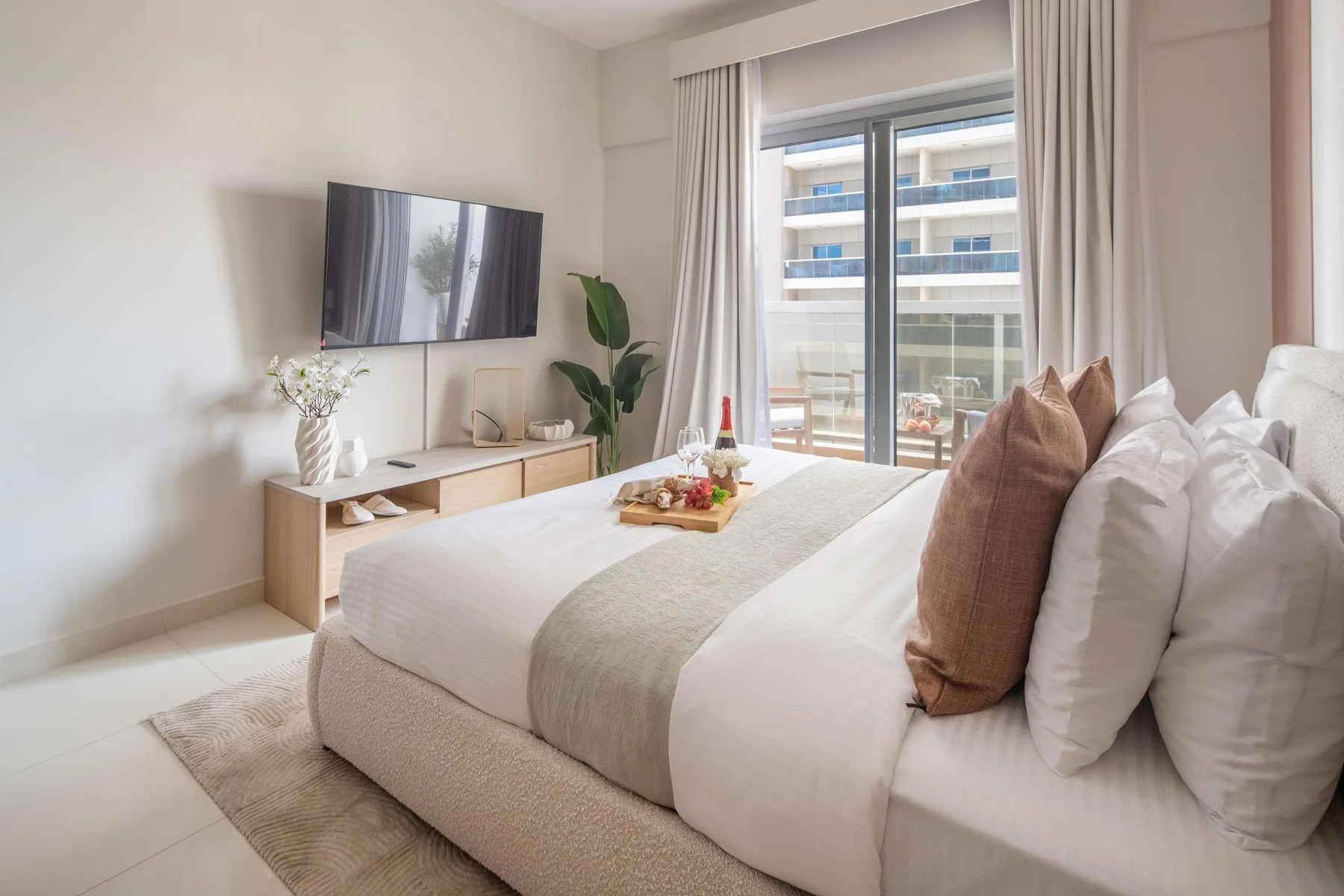 Un dormitorio luminoso con una cama bien tendida junto a una ventana grande.