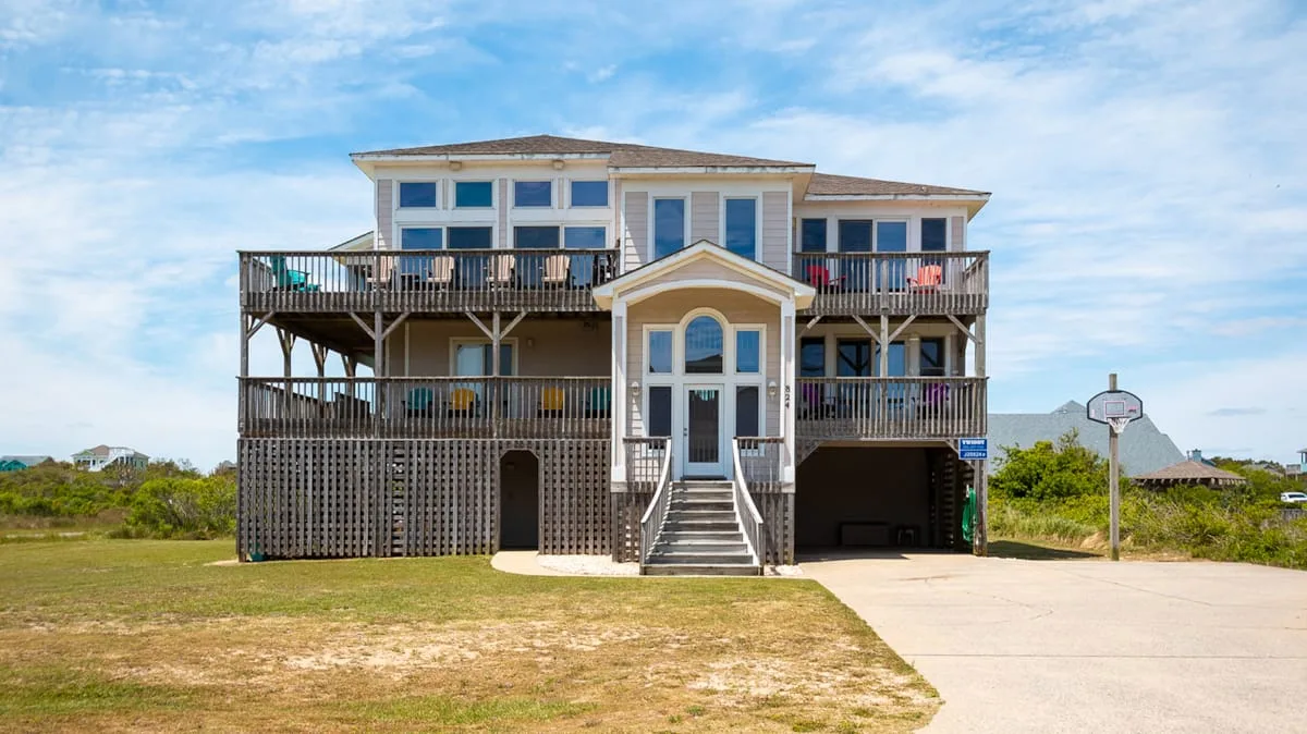 A raised coastal house with broad wooden balconies and a central entrance.