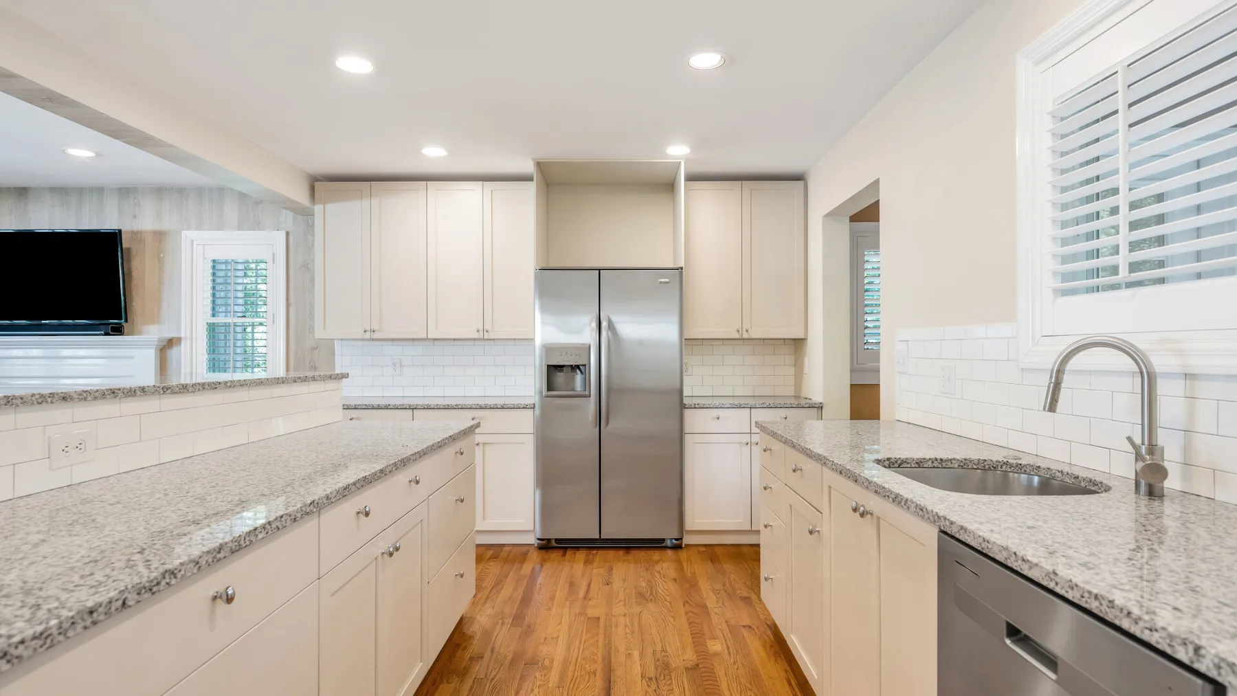 Una cocina luminosa con gabinetes claros, encimeras de granito y electrodomésticos de acero inoxidable.
