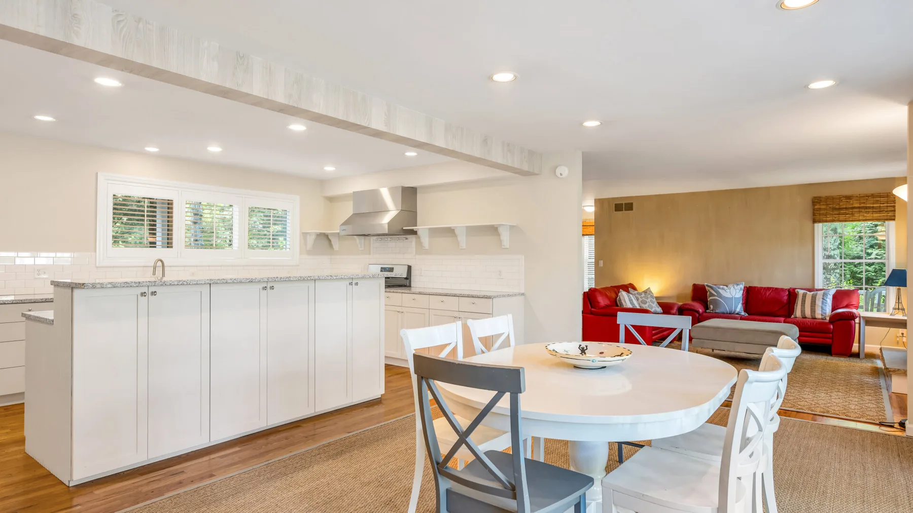 Una cocina y comedor diáfanos, con una zona de asientos rojos detrás de la mesa.