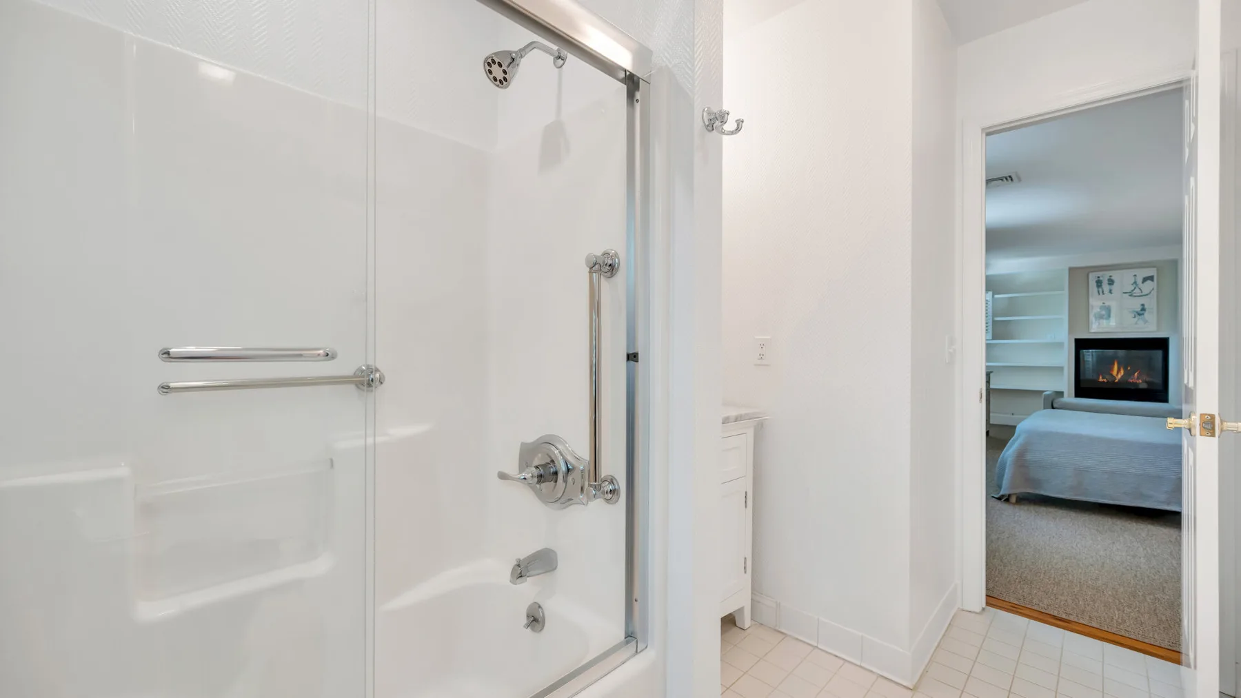 Un baño luminoso con una ducha de vidrio junto a una puerta abierta.