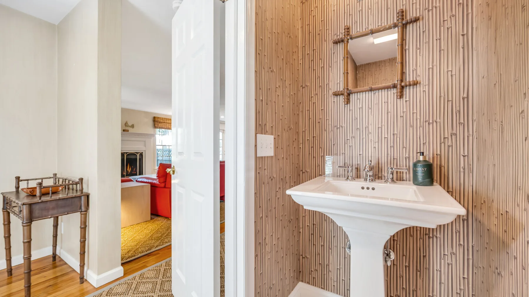 Un baño con un lavabo de pedestal blanco frente a una pared revestida de madera.
