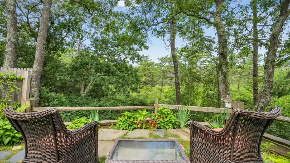 An outdoor patio with two woven seats facing a small square water feature.