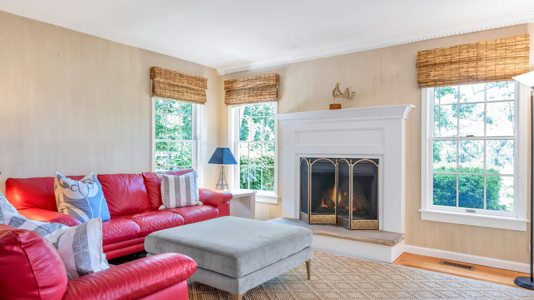 A living room with red seating, a fireplace, and several bright windows.