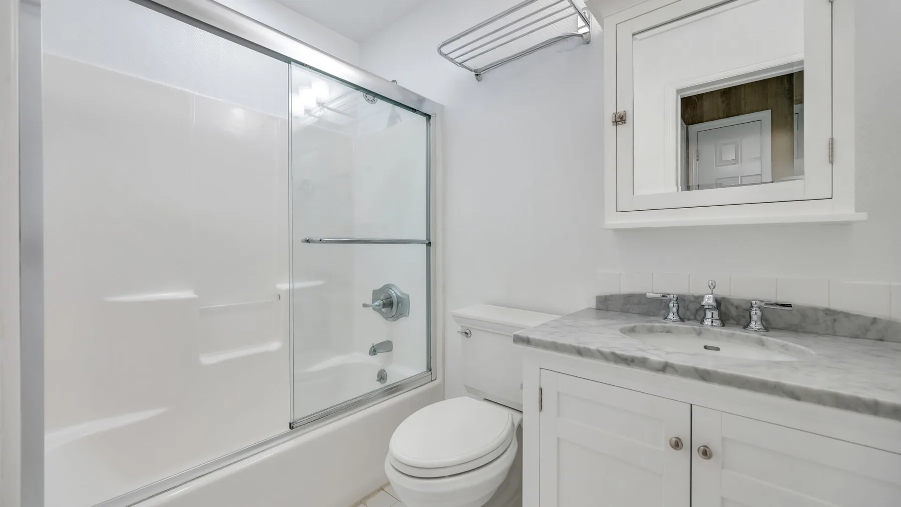 Un baño luminoso con ducha de vidrio, inodoro y lavabo con mueble.