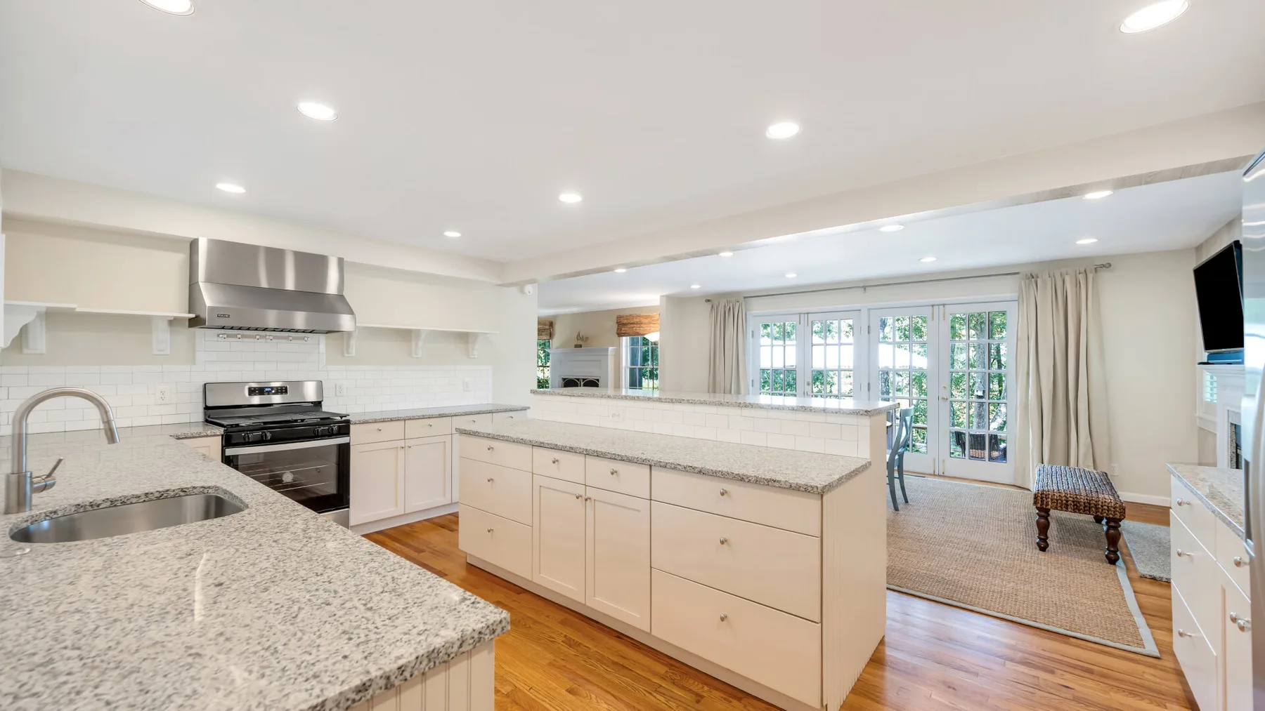 Una cocina luminosa con una isla central y ventanas hacia un comedor.
