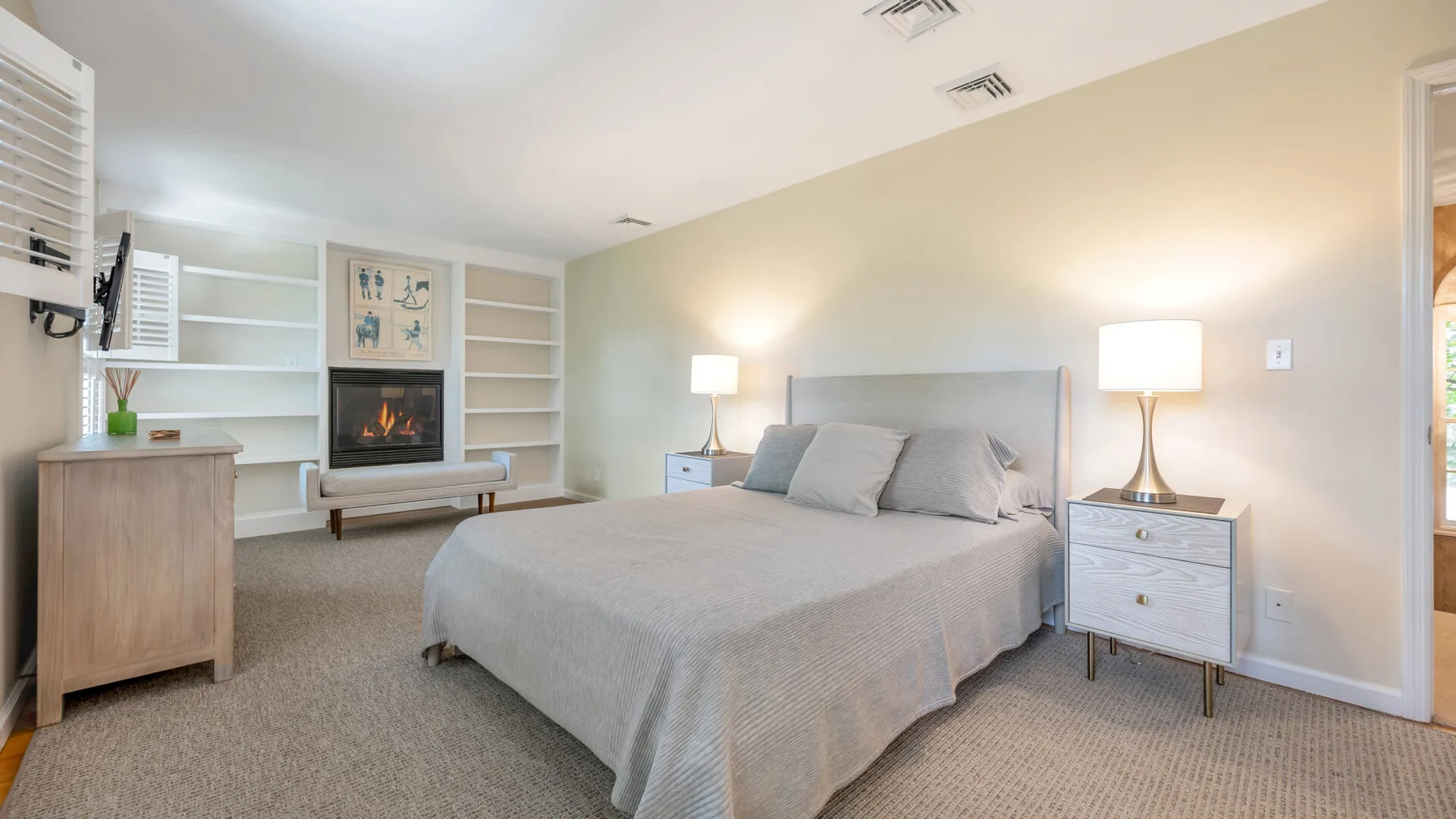 Un dormitorio con cama, mesitas de noche y estanterías empotradas.