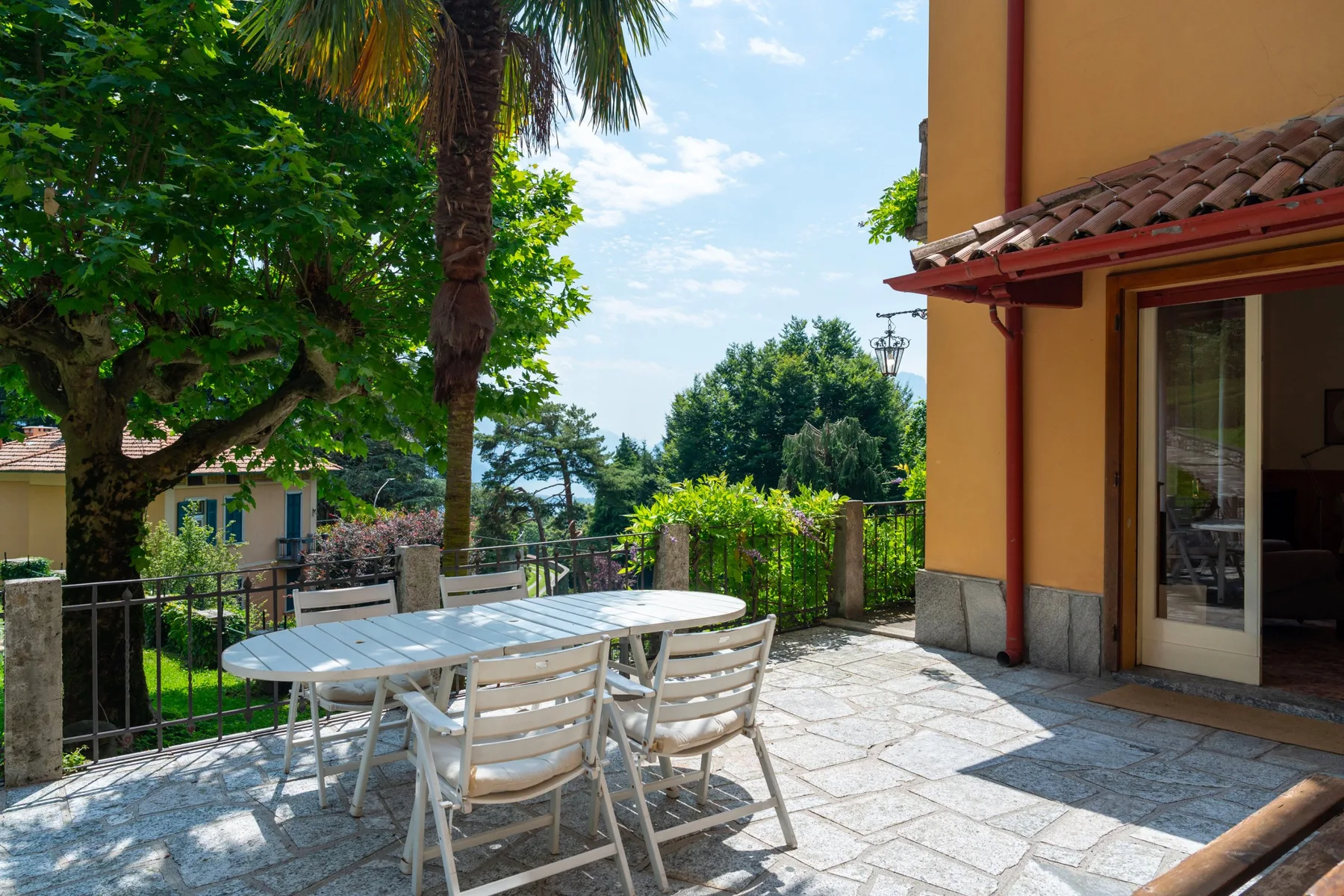 A sunny outdoor patio with a dining table and chairs beside a house.