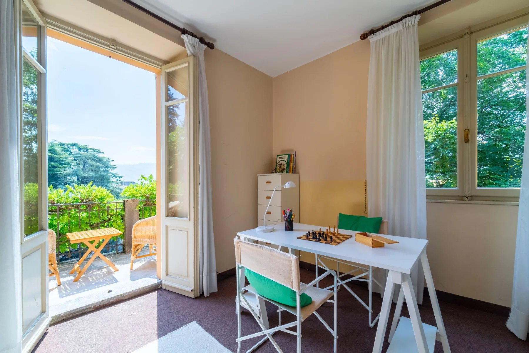 A bright dining area with a table and chairs beside an open door to a balcony.