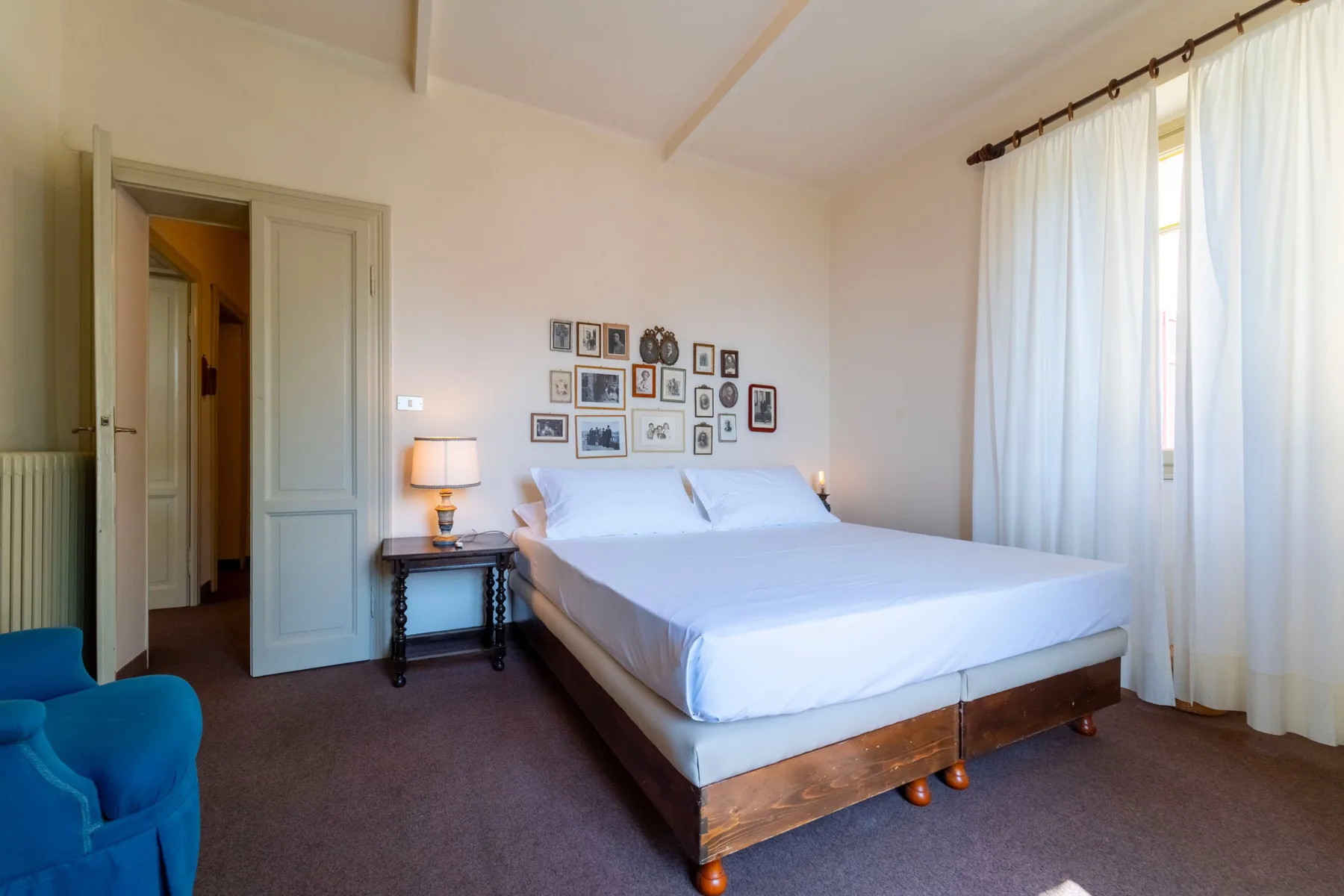 A bedroom with a neatly made bed and framed pictures above it.