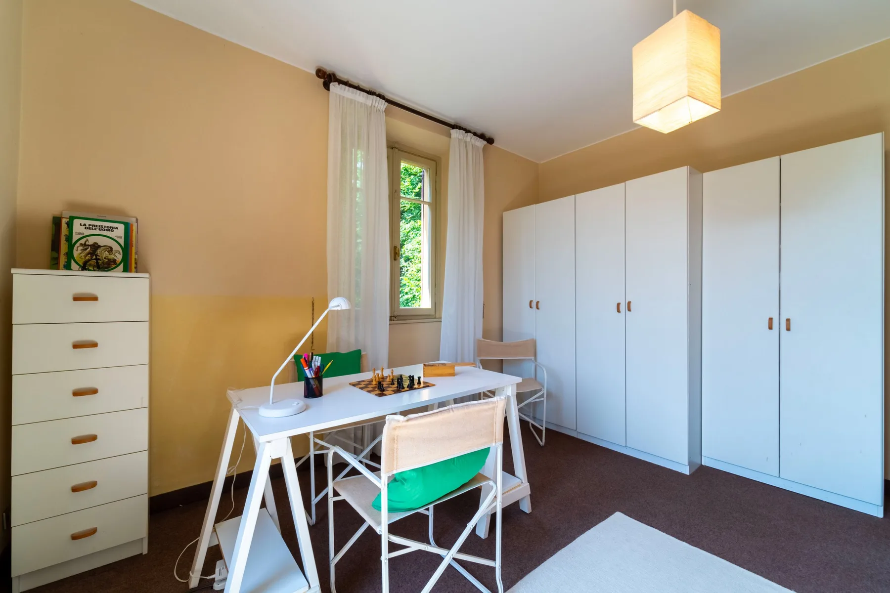 A bright room with a table, chairs, and white built-in storage.