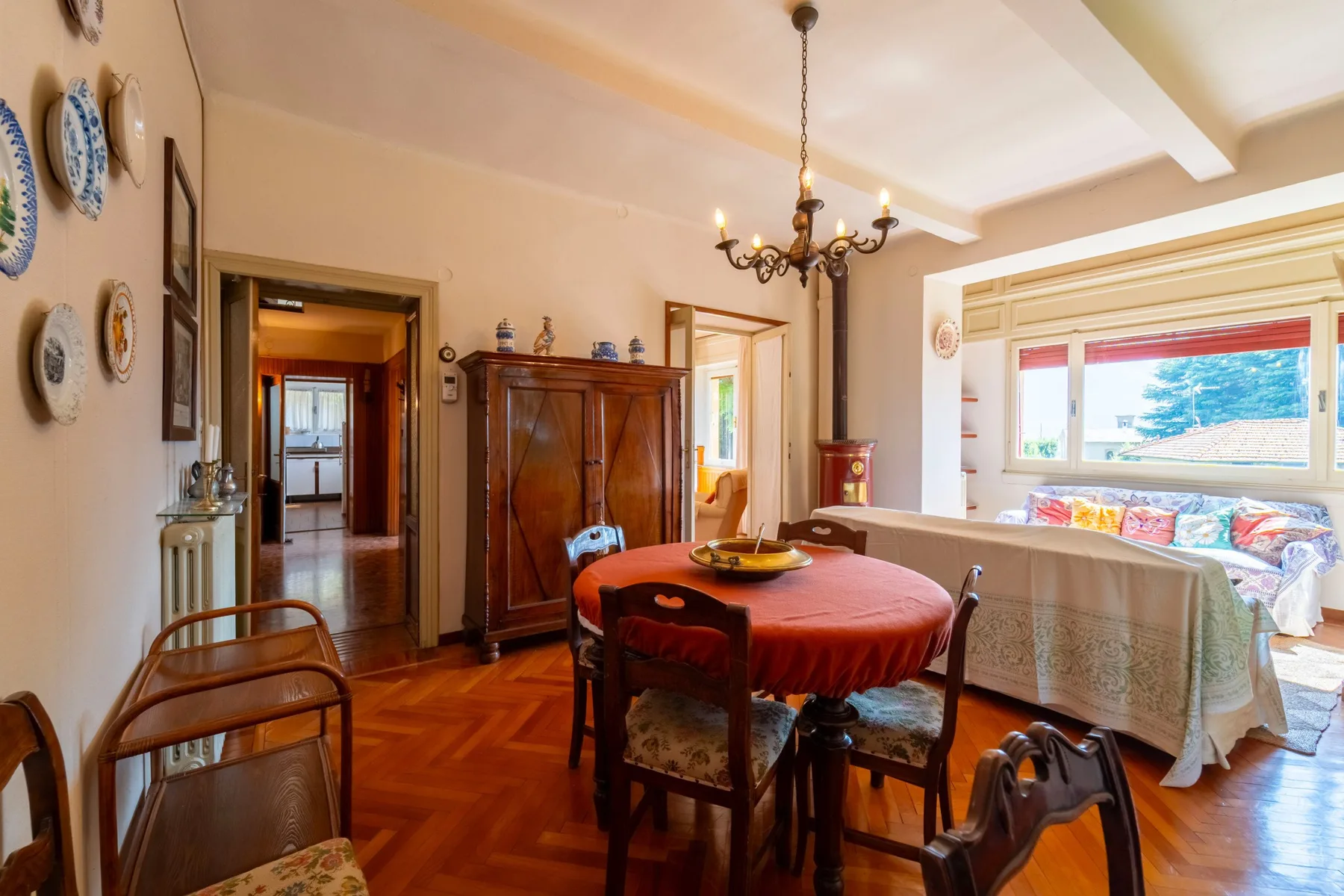 A dining area with a round table, wooden chairs, and a large window.