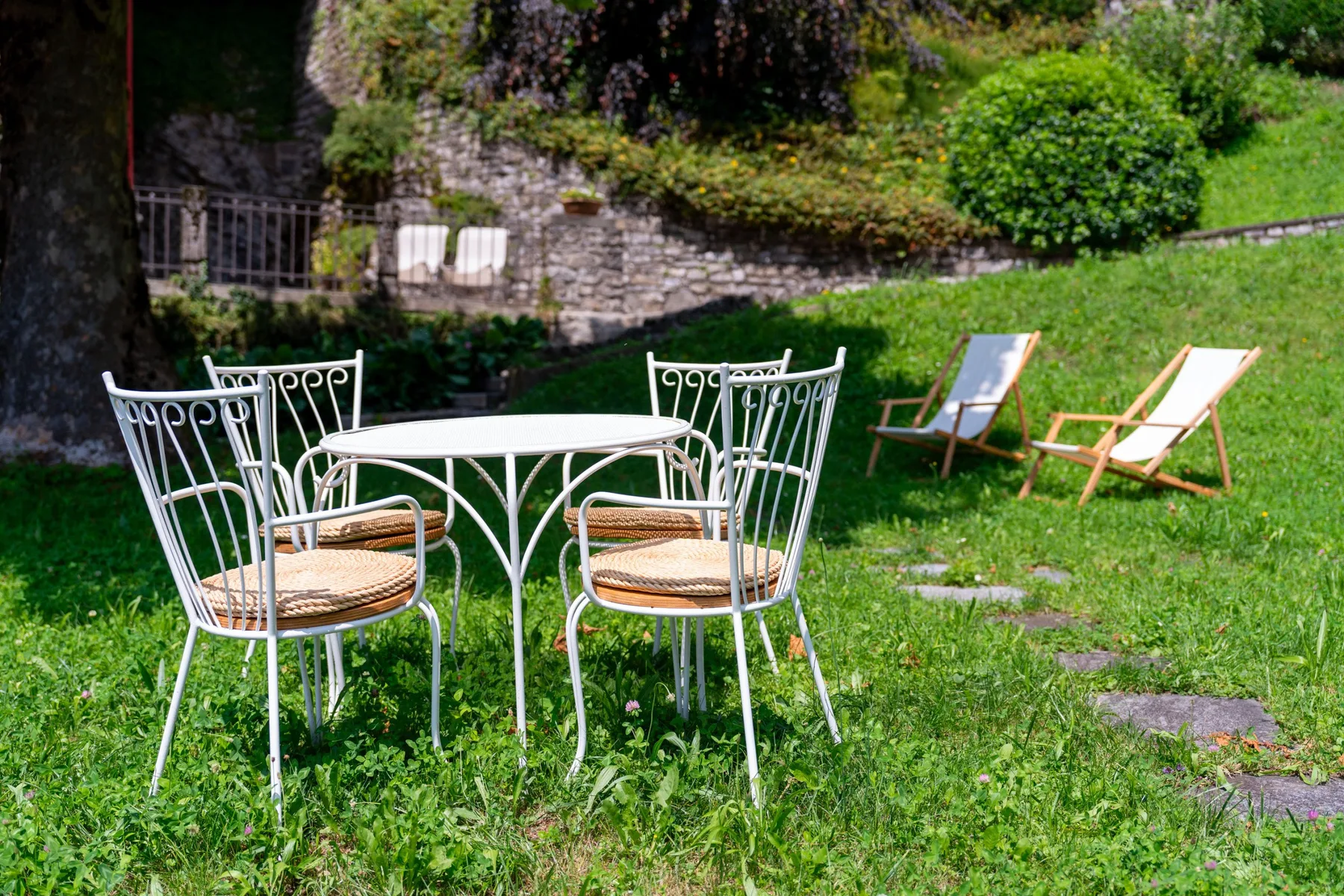 A garden seating area with a metal table and chairs on the lawn.