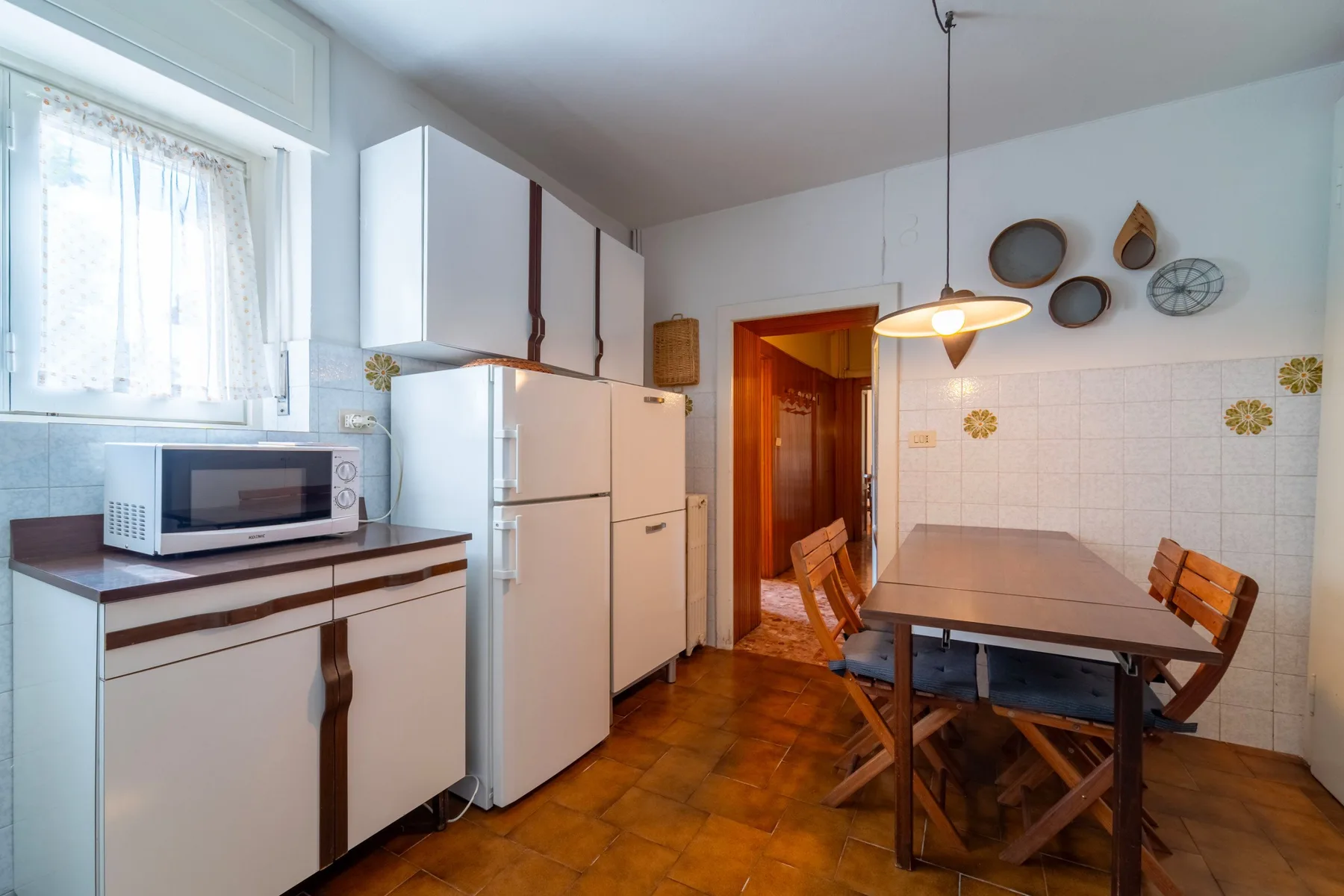 A kitchen with white cabinets, a refrigerator, and a dining table.