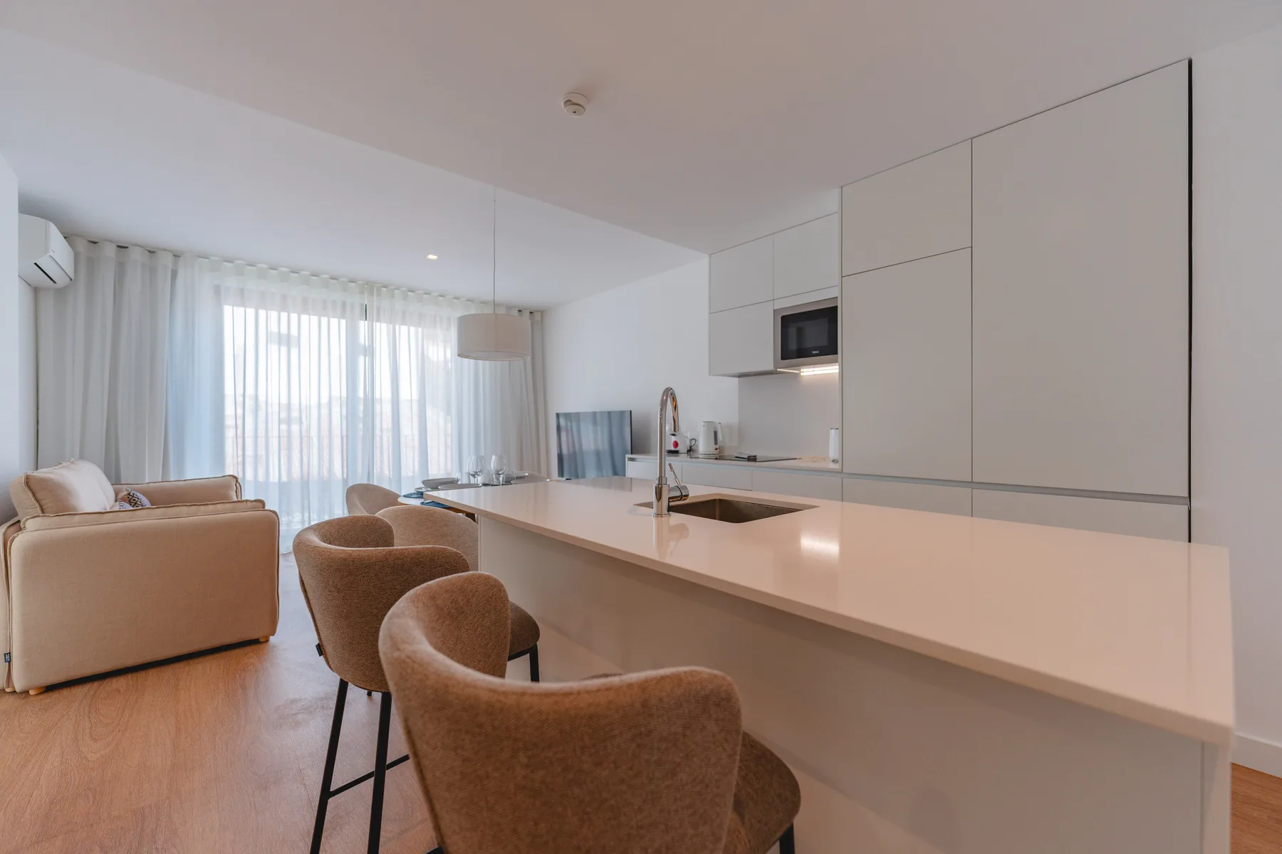 Una cocina y comedor diáfanos y luminosos, con una barra larga y asientos.